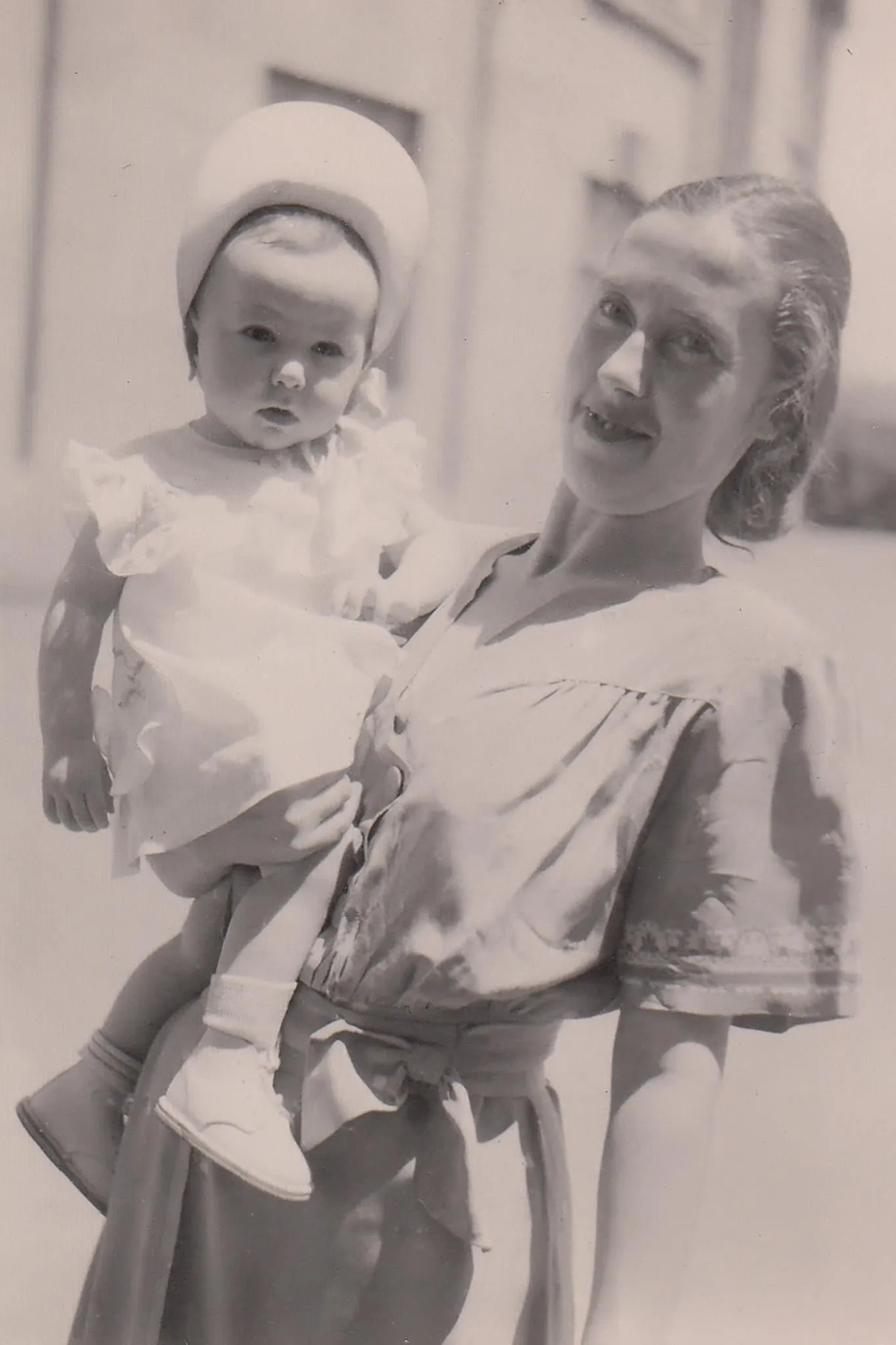 Photographie ancienne : une femme tient un jeune enfant dans ses bras.