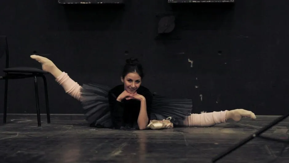 Une danseuse étirée au sol sur scène, en noir et blanc.