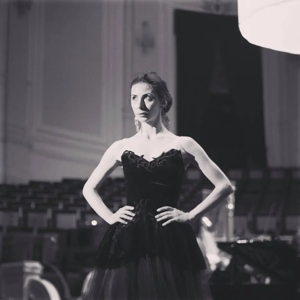 Une danseuse salue sur scène en robe noire, en noir et blanc.