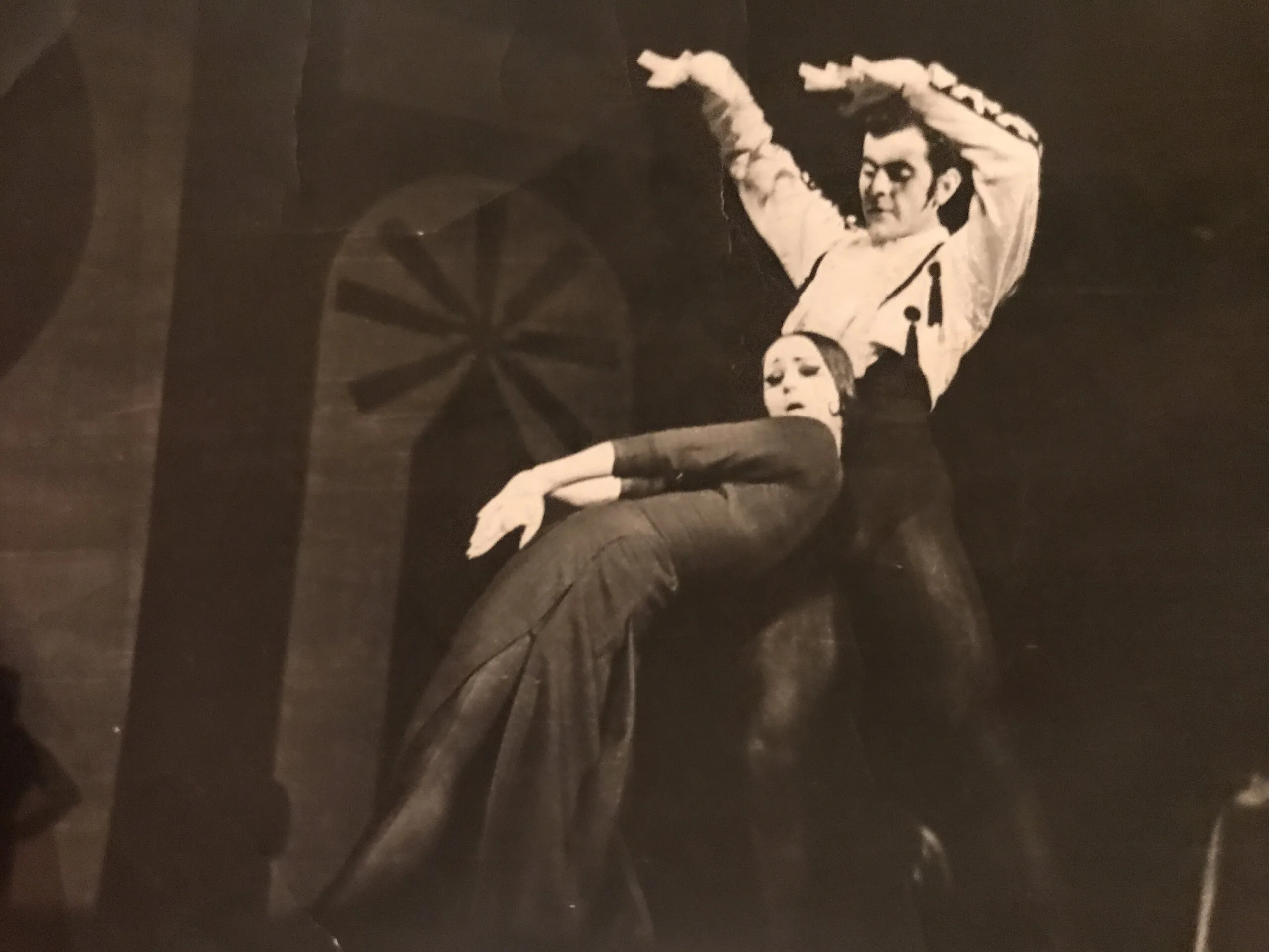 Tirage sépia : un danseur soutient une ballerine cambrée en arrière, deux roues peintes sur le décor.