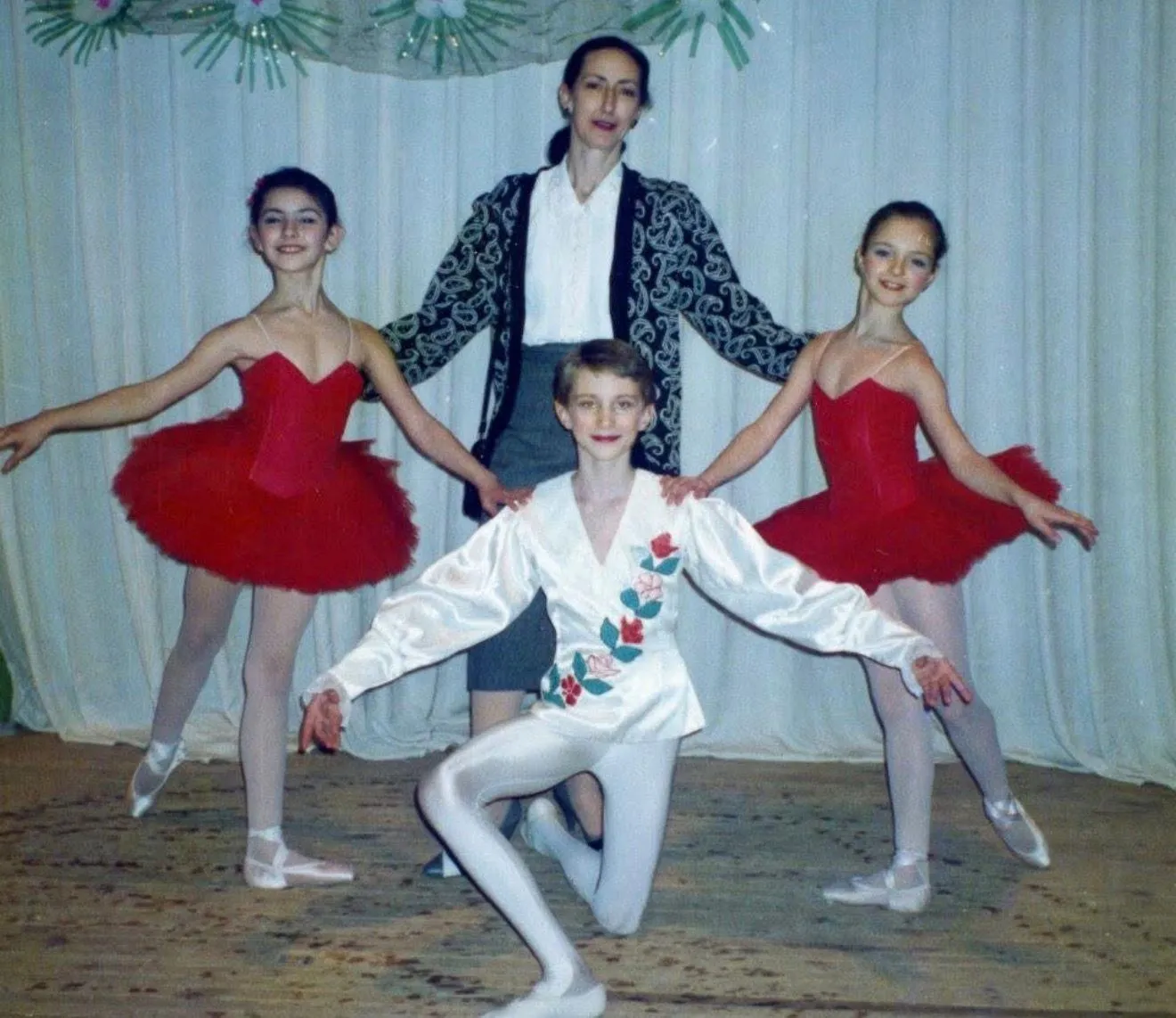 En studio, un groupe d'élèves en costume de scène entoure leur professeur.
