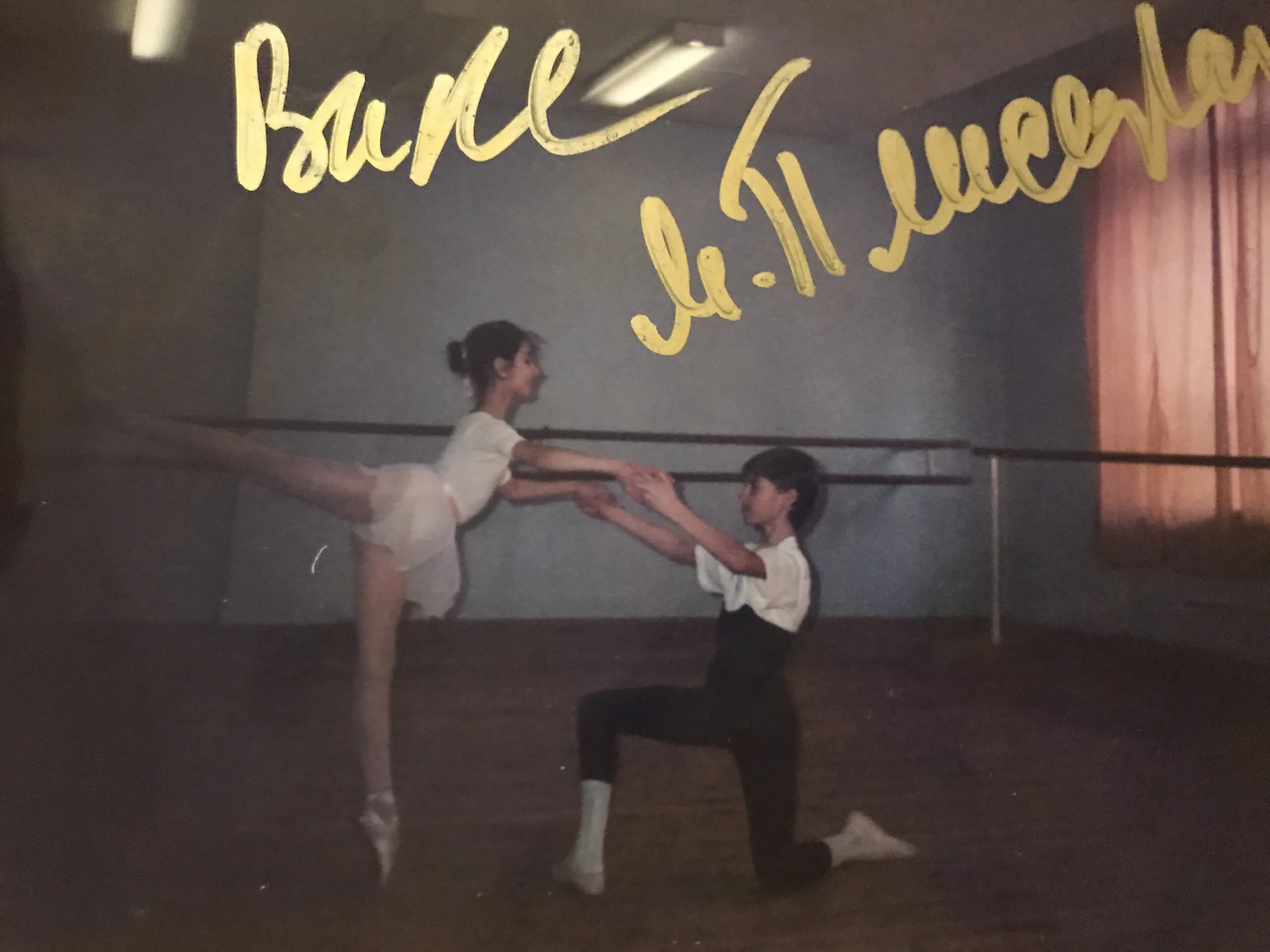 Tirage dédicacé à l'encre dorée : une jeune danseuse en arabesque à la barre, un garçon agenouillé lui tenant les mains.