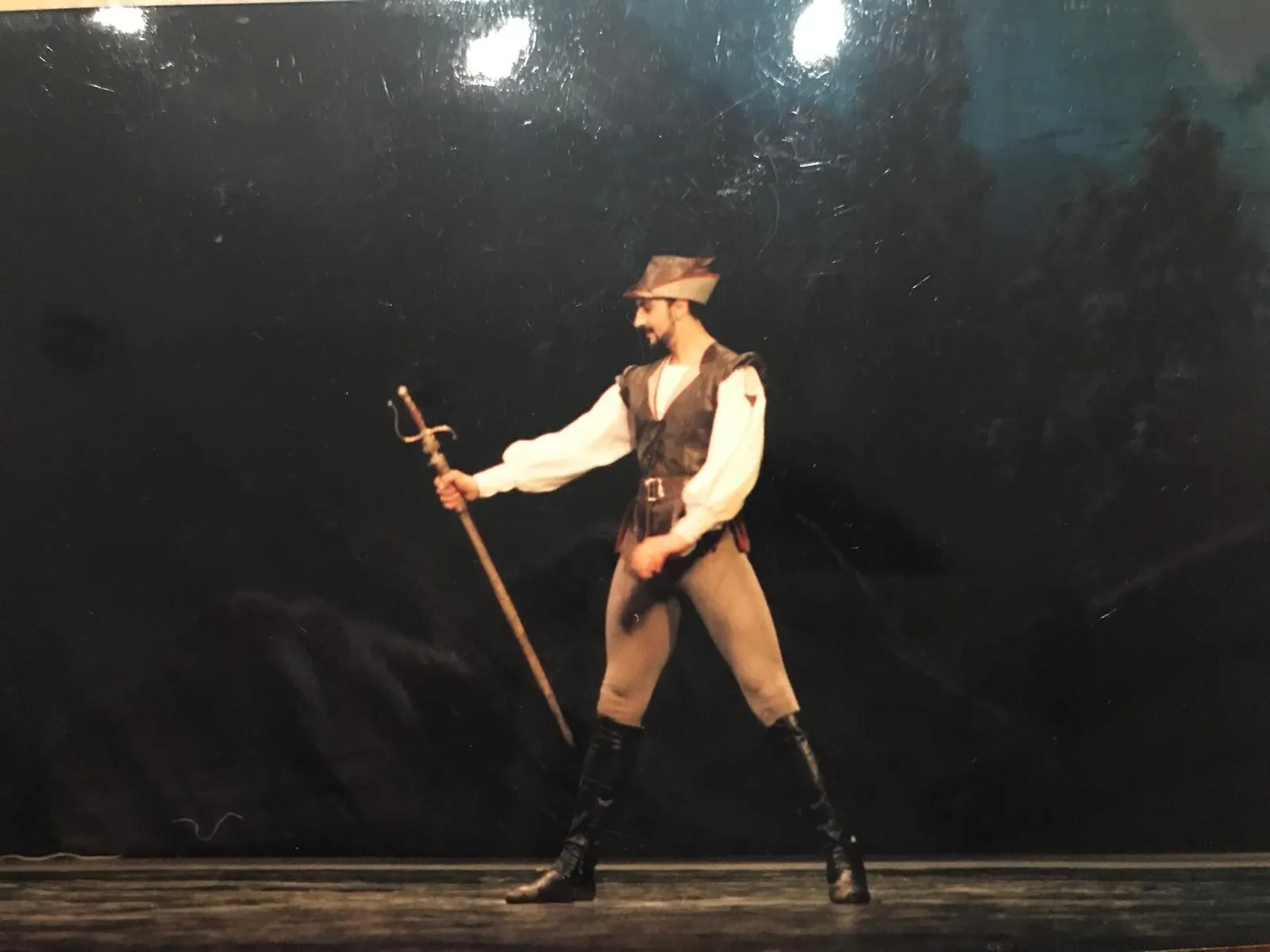 Un danseur en costume de caractère, une rapière à la main, sur une scène d'époque.