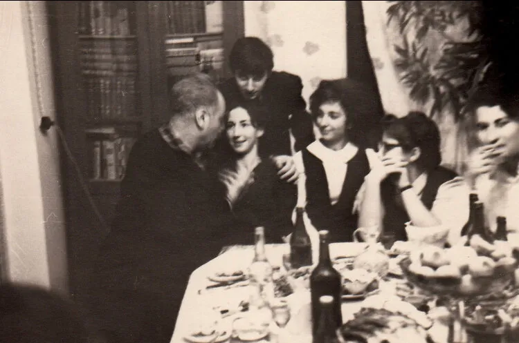 Autour d'une table dressée, une réunion de famille photographiée en noir et blanc.