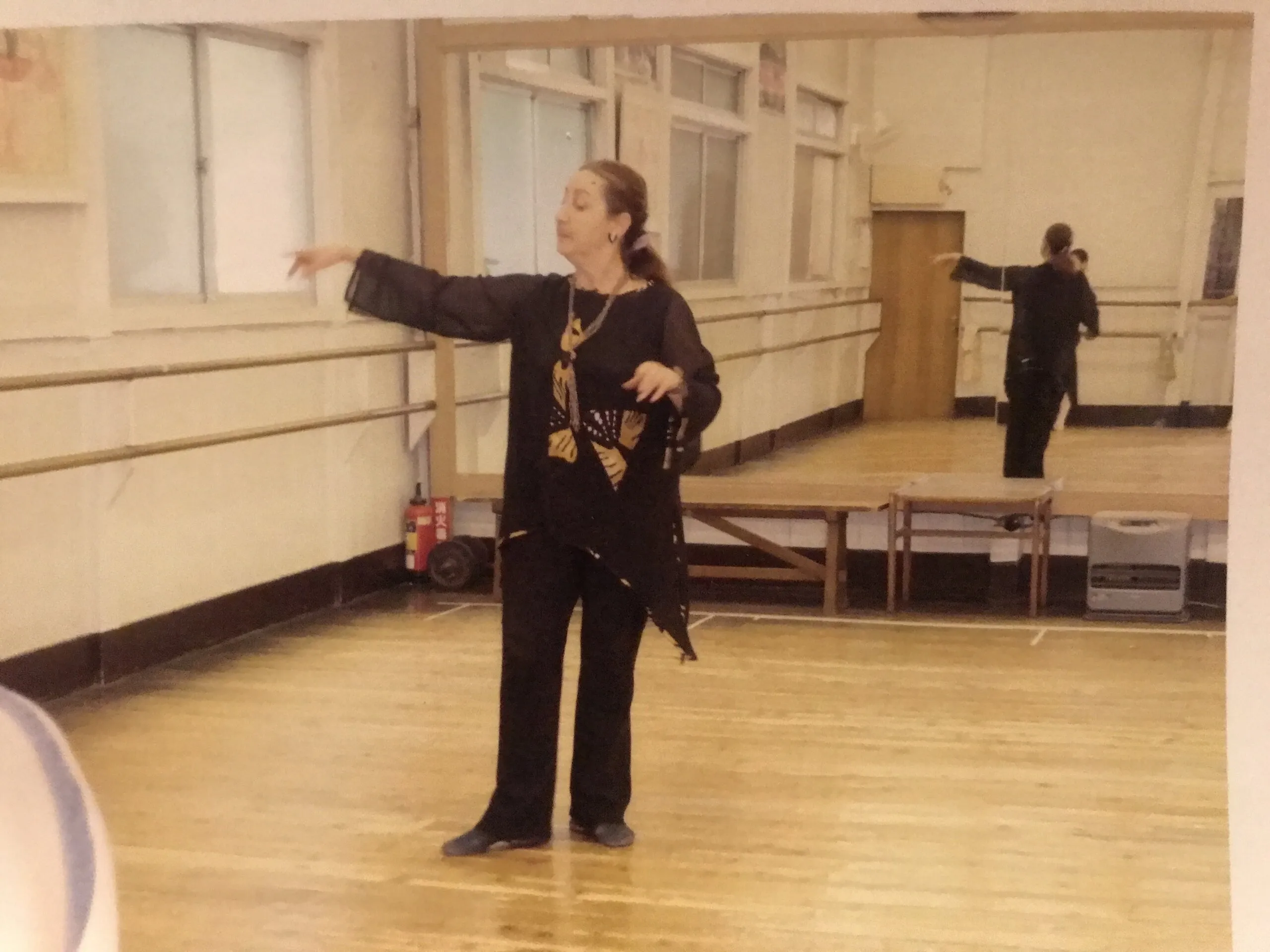 Une professeure indique une direction au milieu d'un studio de danse.