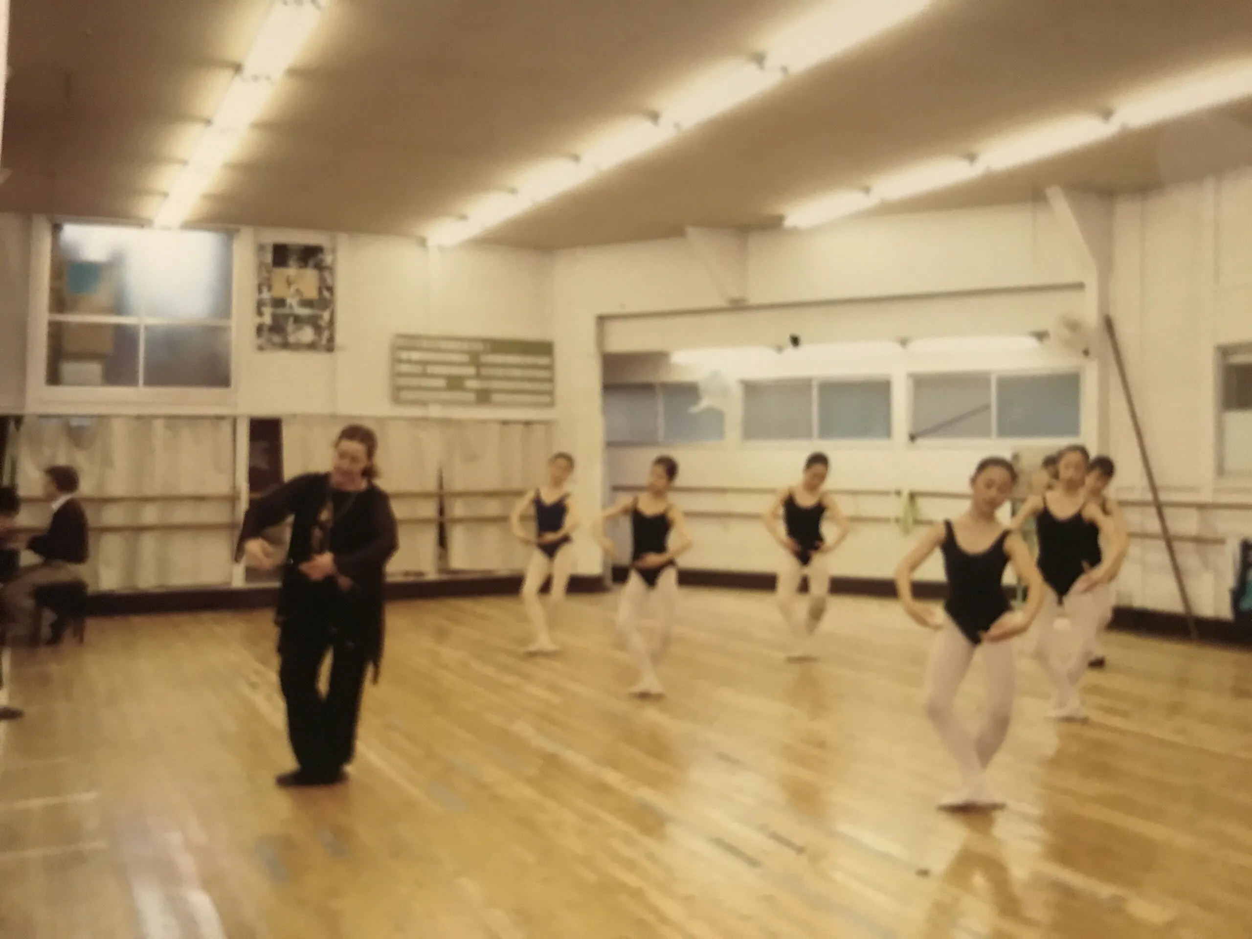 Cours à la barre dans un studio, les élèves alignées le long du miroir, la professeure parmi elles.