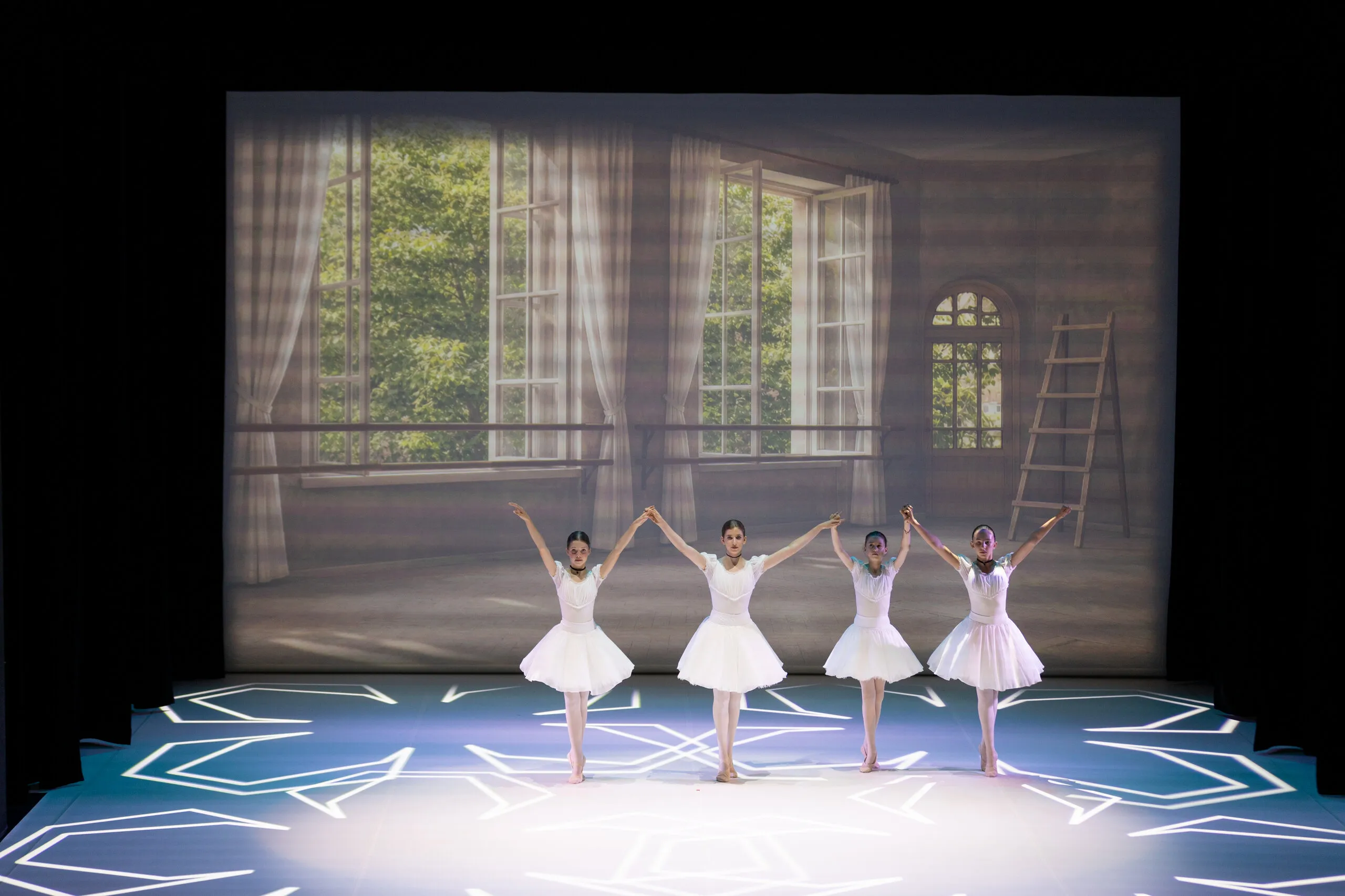Four students in white open the performance, the classroom as a backdrop.