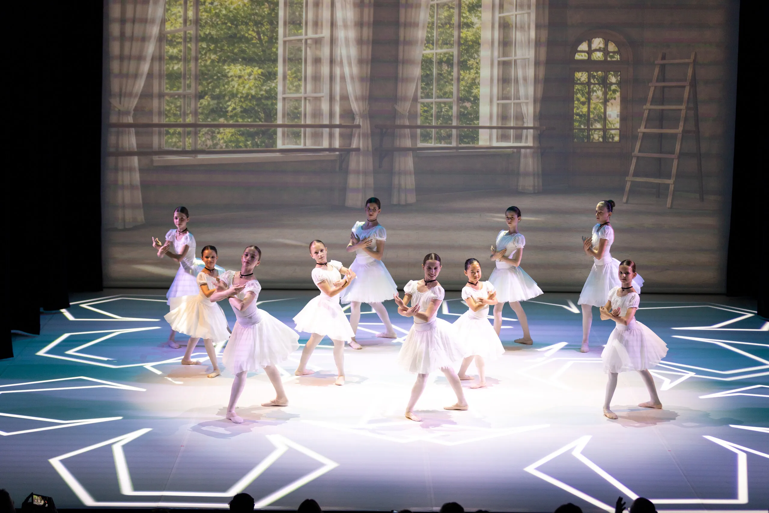 The group in white spread across the stage, a snowflake pattern on the floor.
