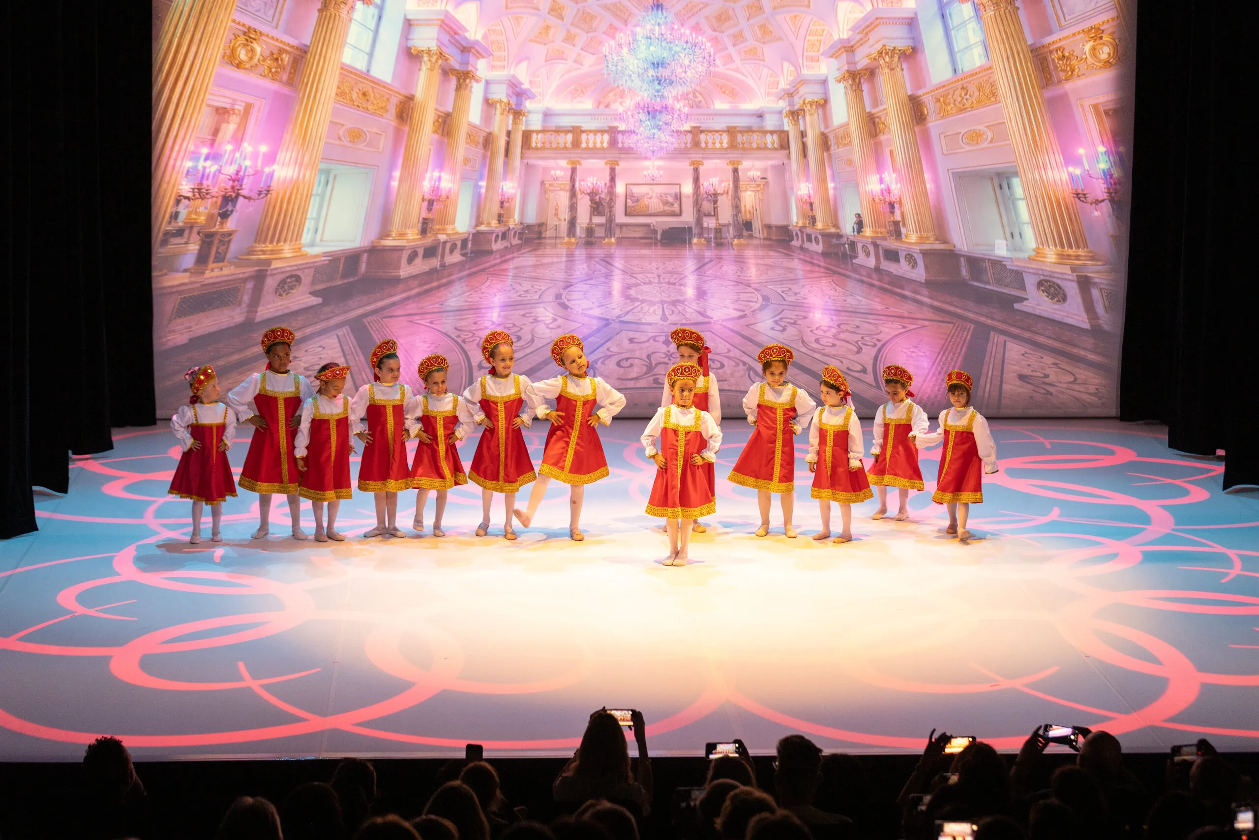Les jeunes élèves en coiffes traditionnelles rouge et or, pendant les divertissements.