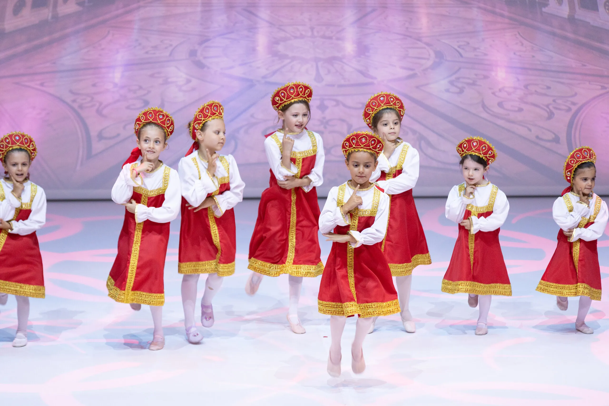 The young students in red and gold costumes, mid step.