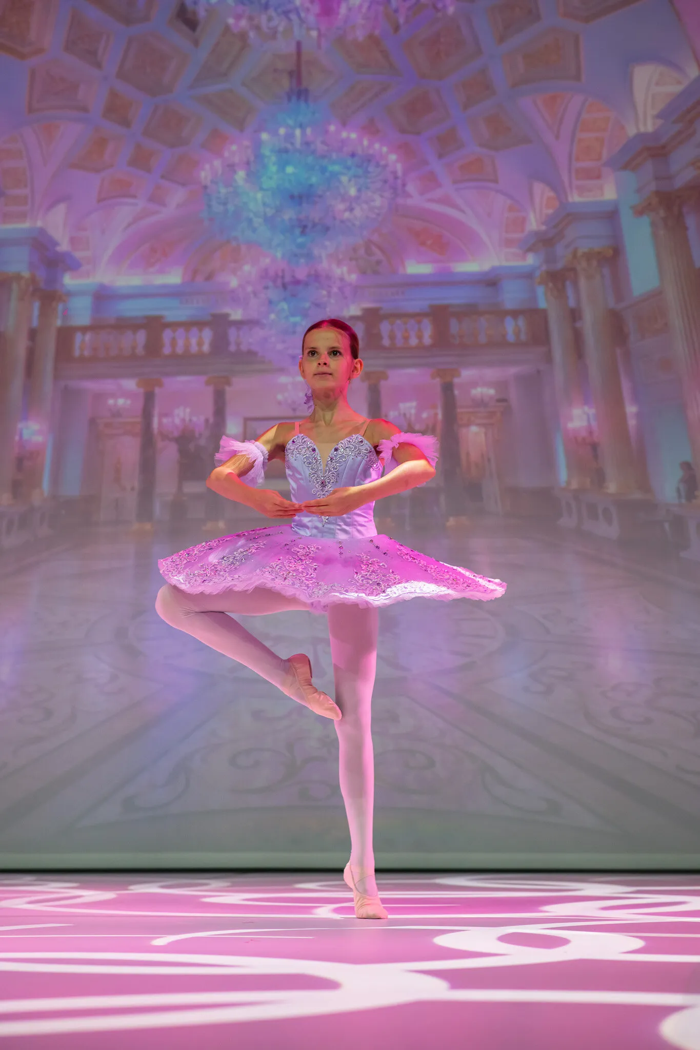 A student in a pink tutu, in retiré before the palace set.