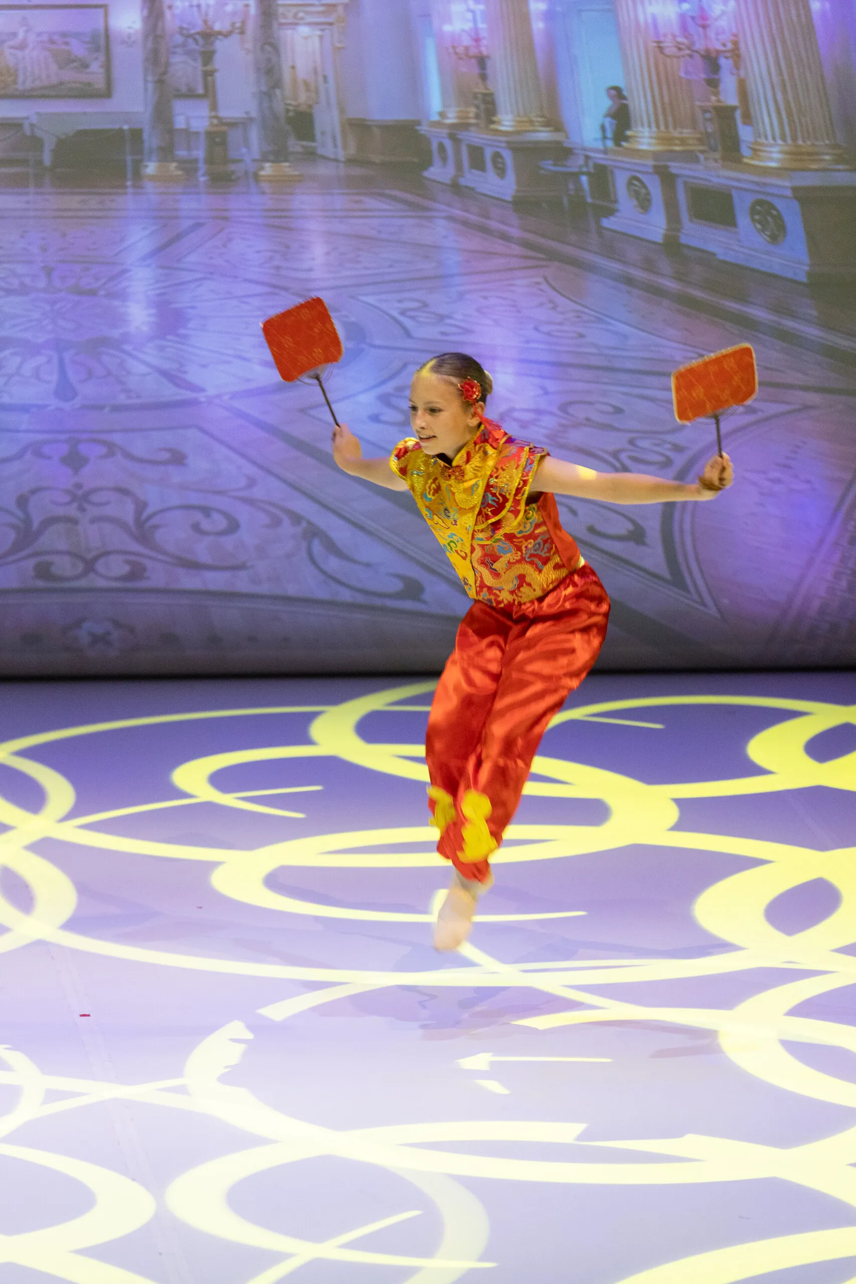 The Chinese dance, a student in red and gold with a fan in each hand.