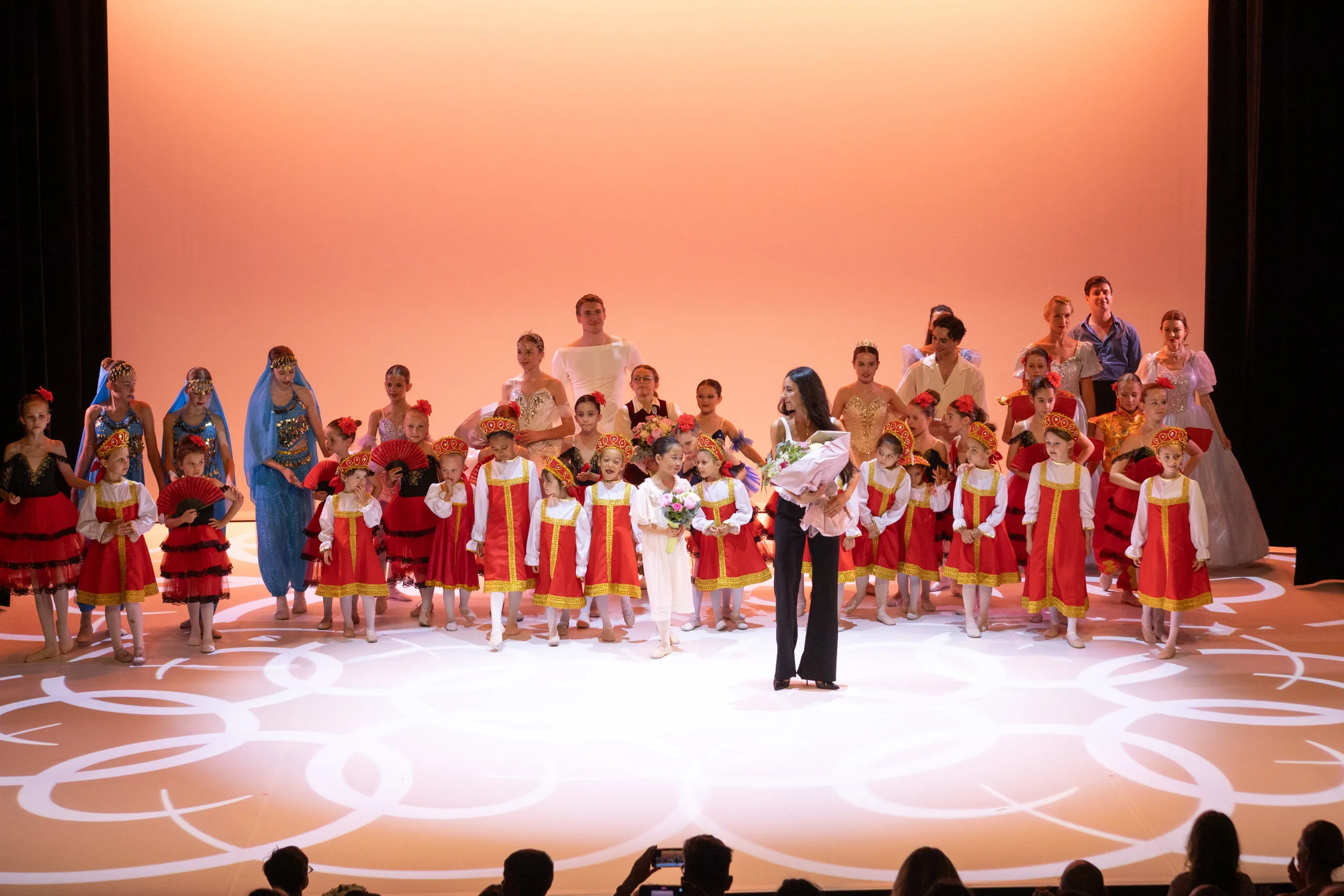 The curtain call, the whole company with the founder at the centre of the stage.