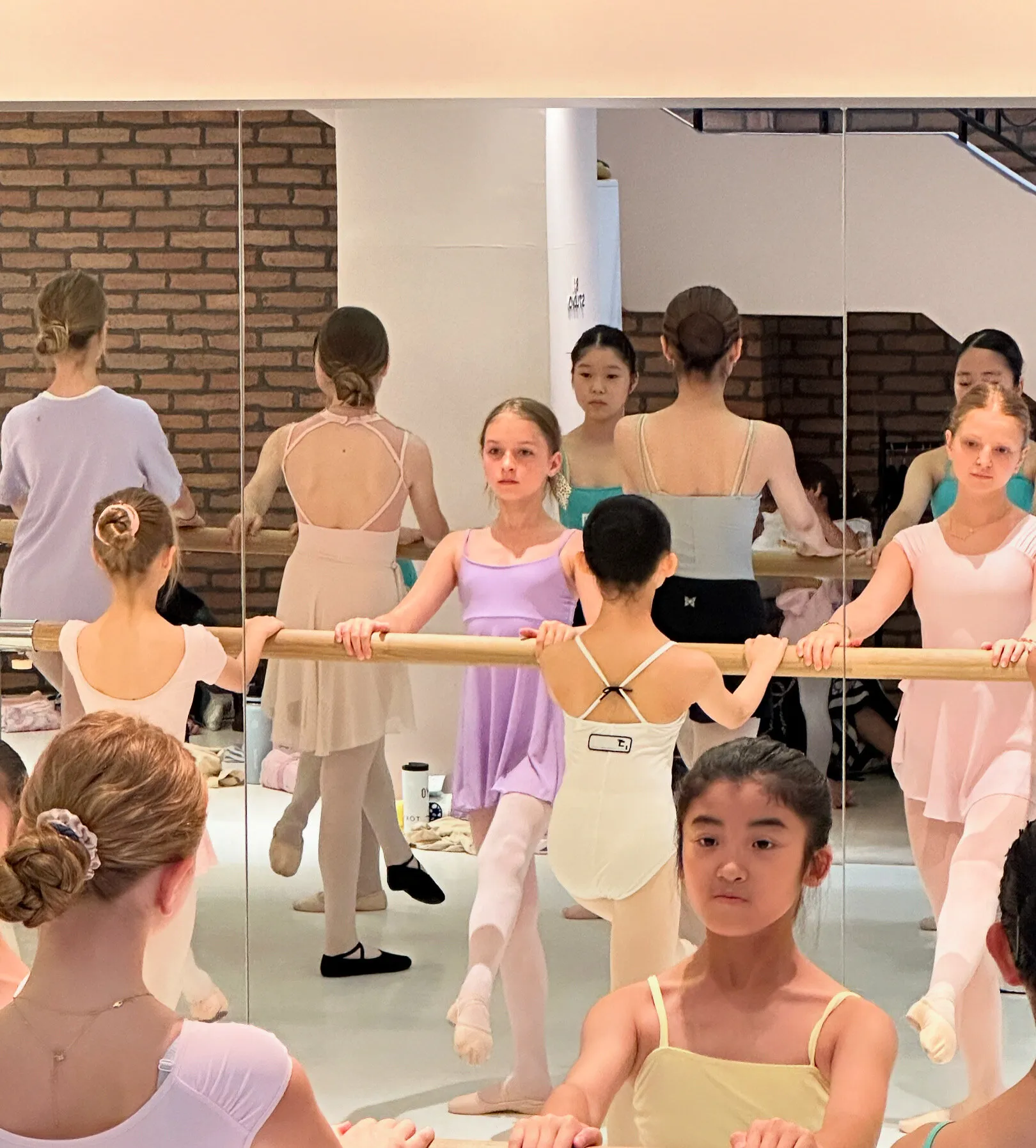 Cours partagé à la barre, les élèves des deux écoles dans le miroir du studio.
