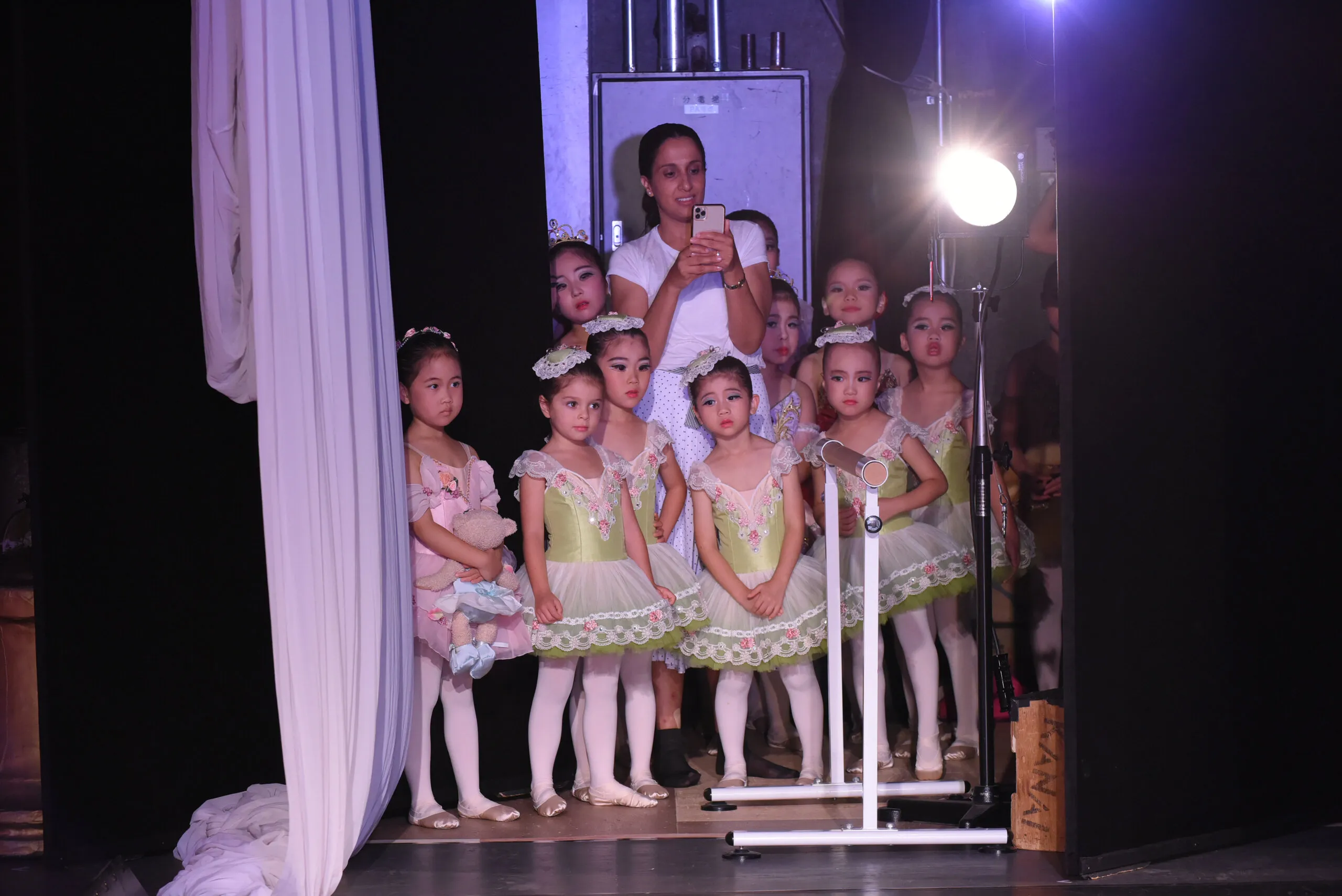 Les petites attendent en coulisses, dans la lumière du projecteur.
