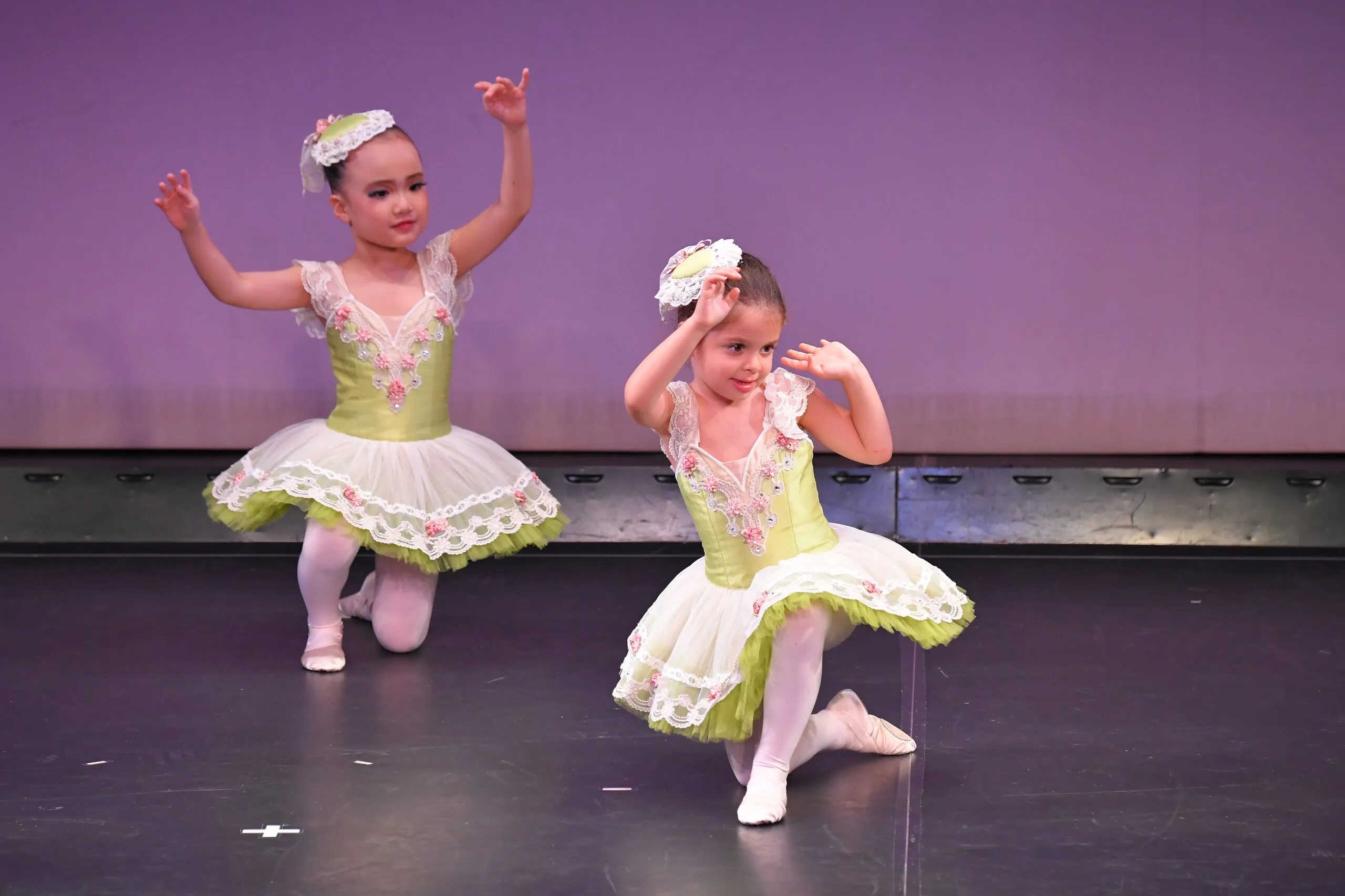 Deux petites en tutus verts et blancs, genou à terre sur scène.