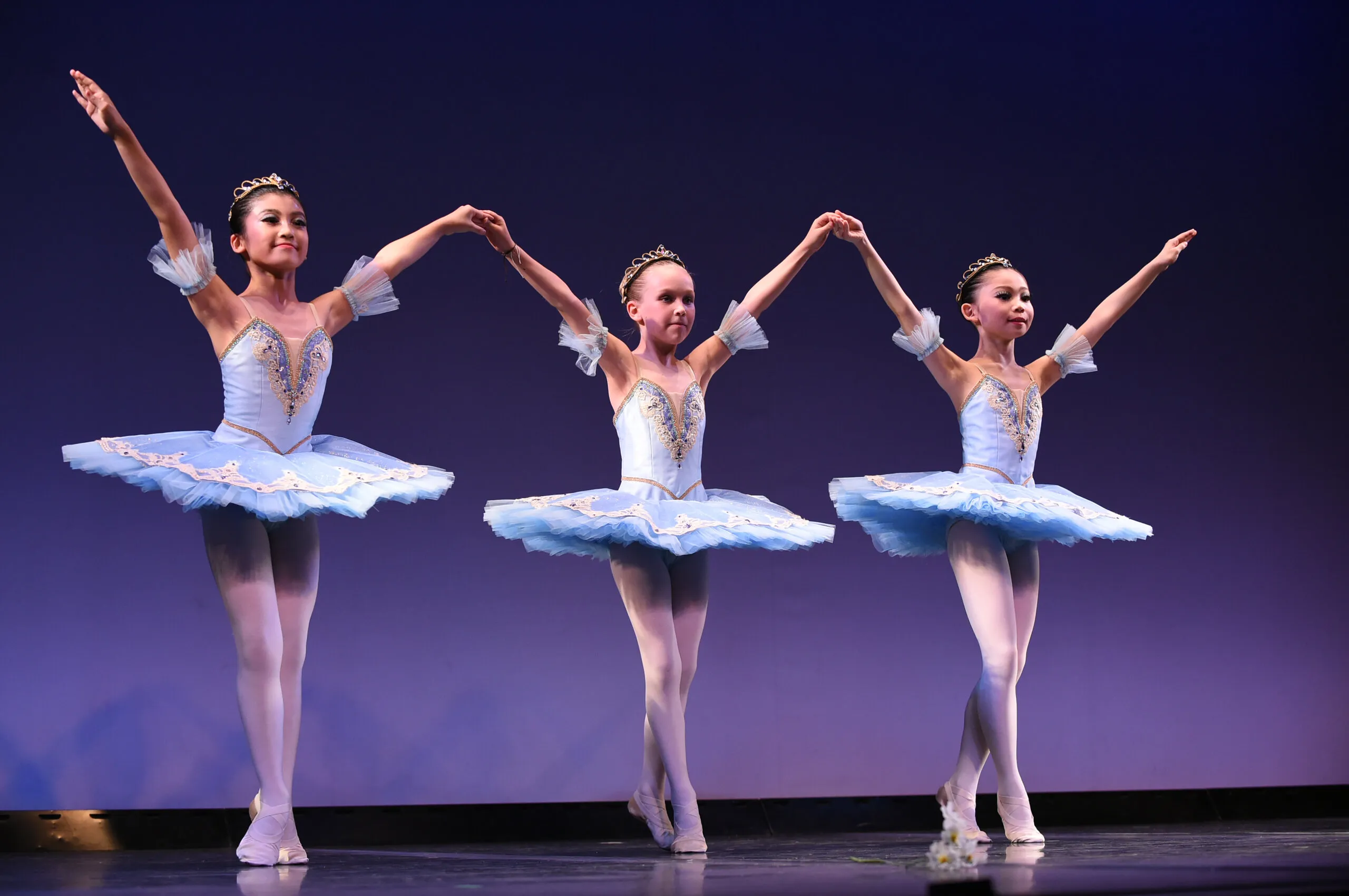 Trio en tutus bleu pâle, mains levées et réunies.