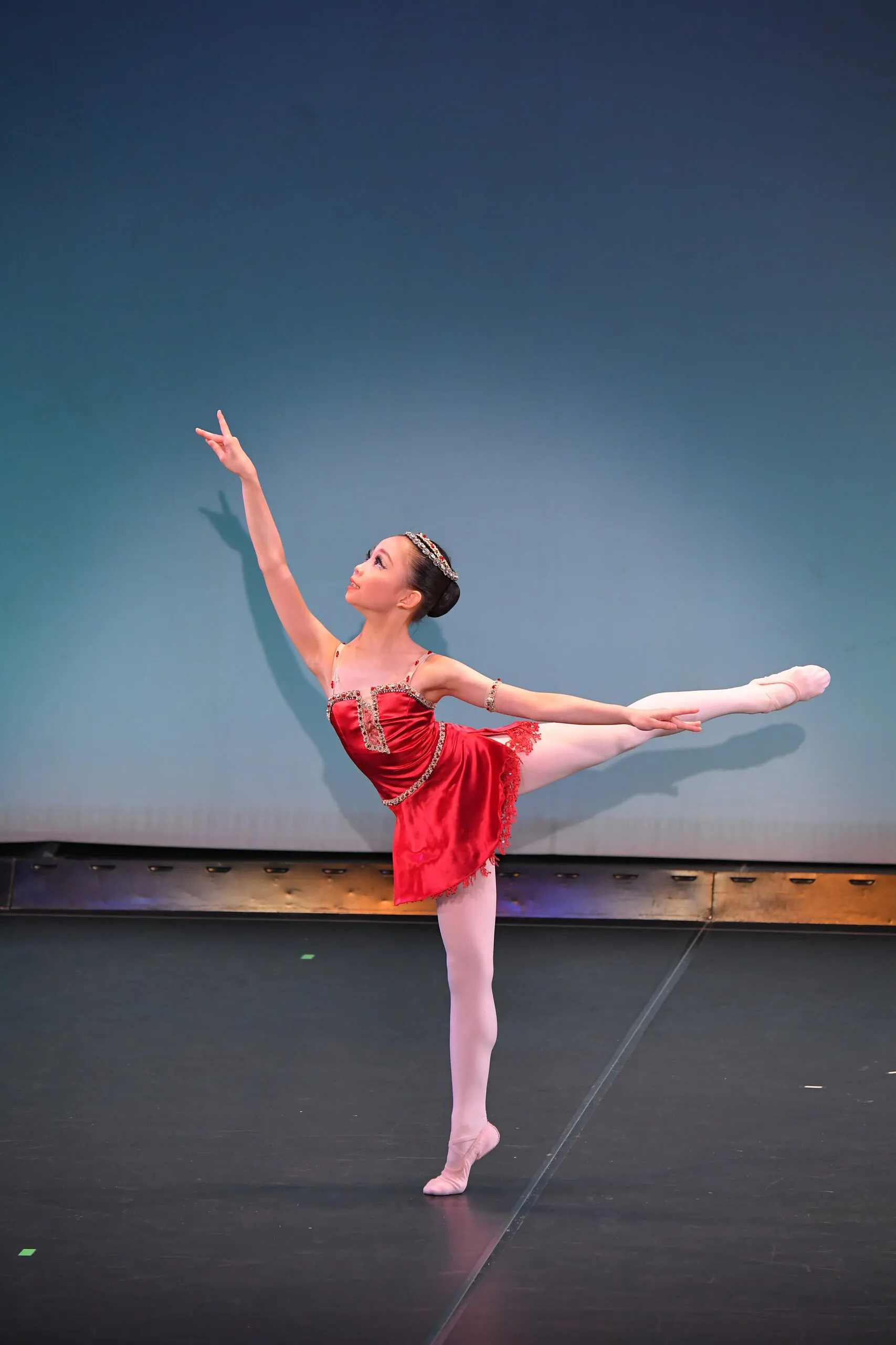 Arabesque en costume rouge, sur le fond bleu de la scène.