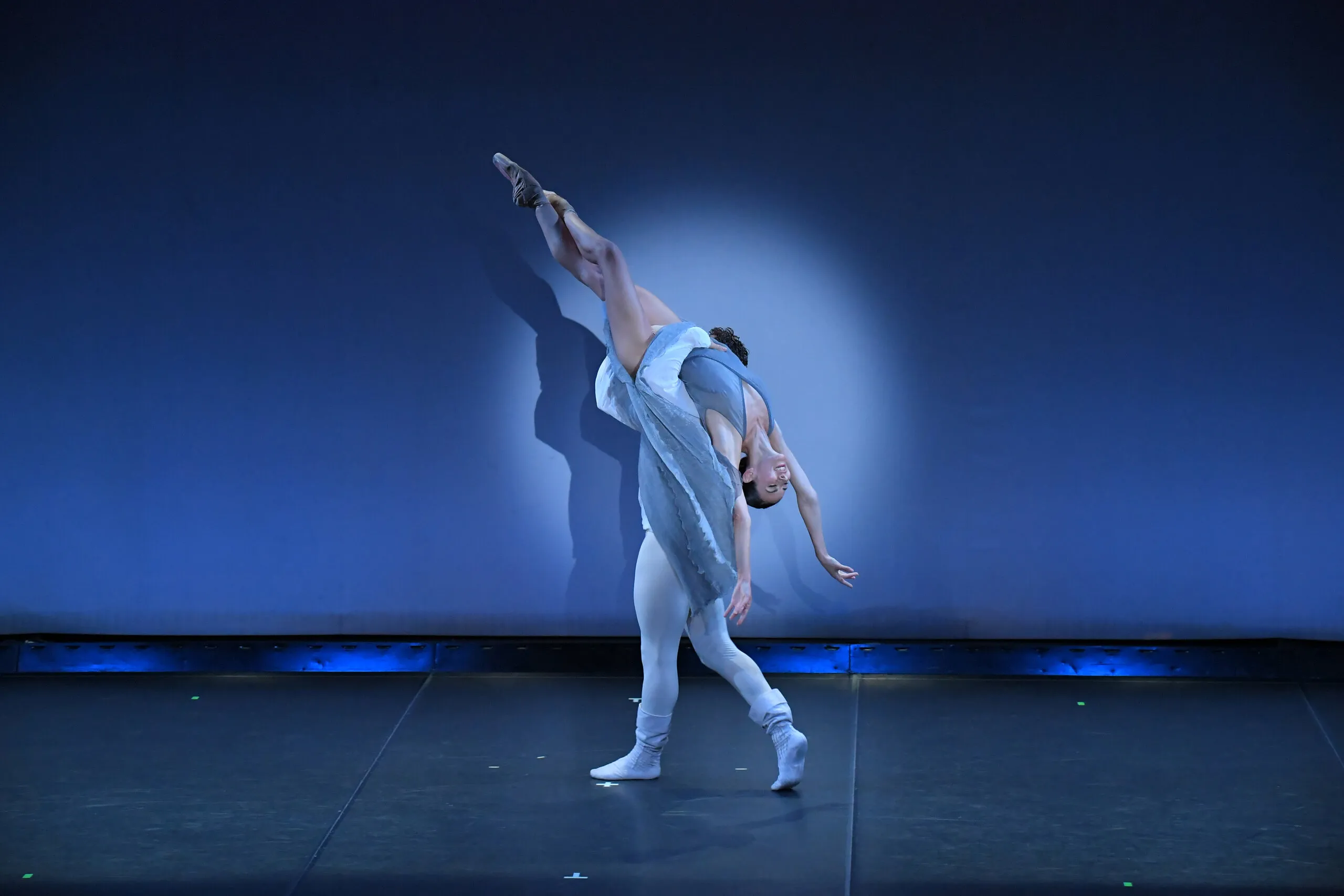 Pas de deux dans une lumière bleue, la danseuse en cambré.