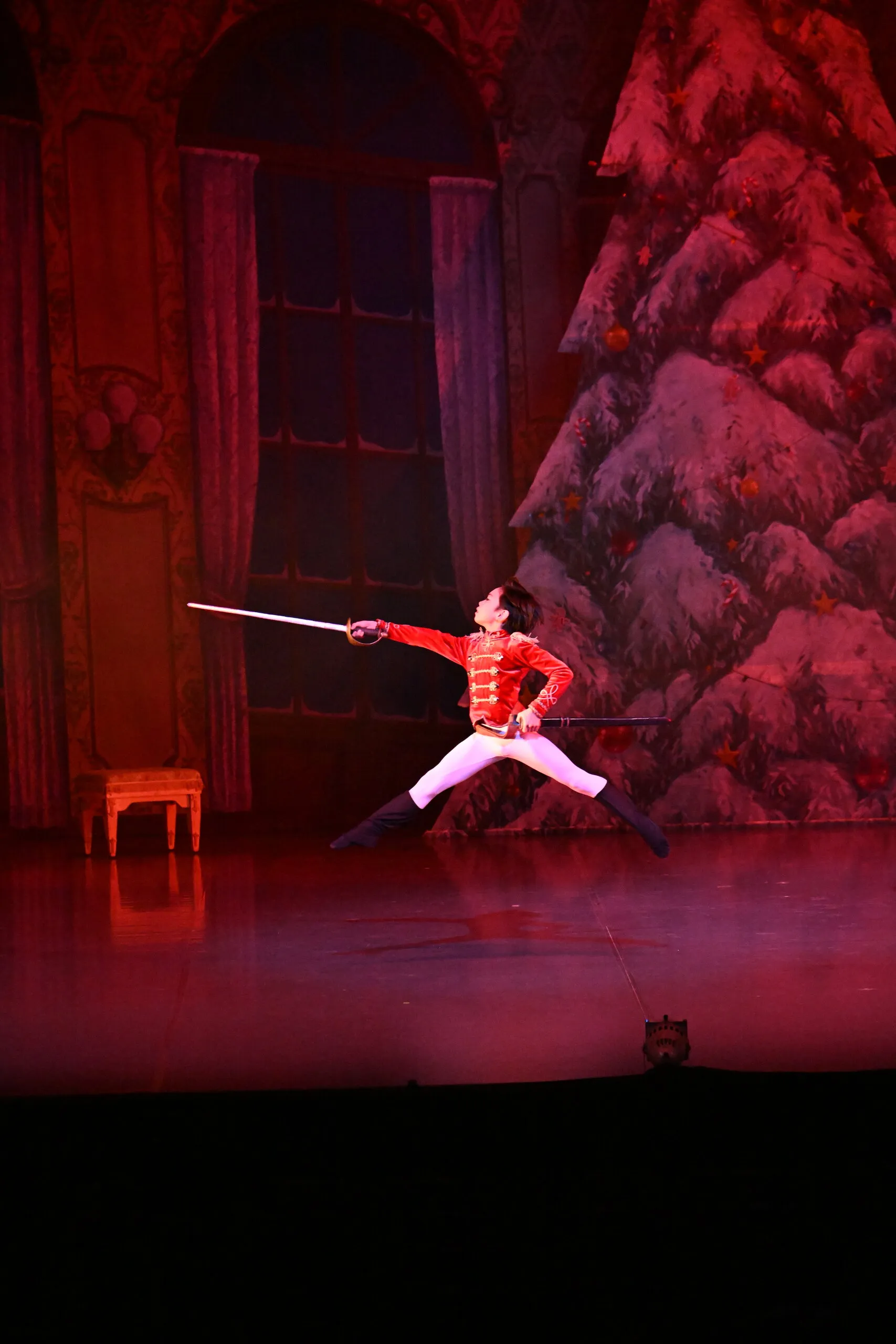 Le soldat en rouge lève son épée, la scène baignée de lumière rouge.