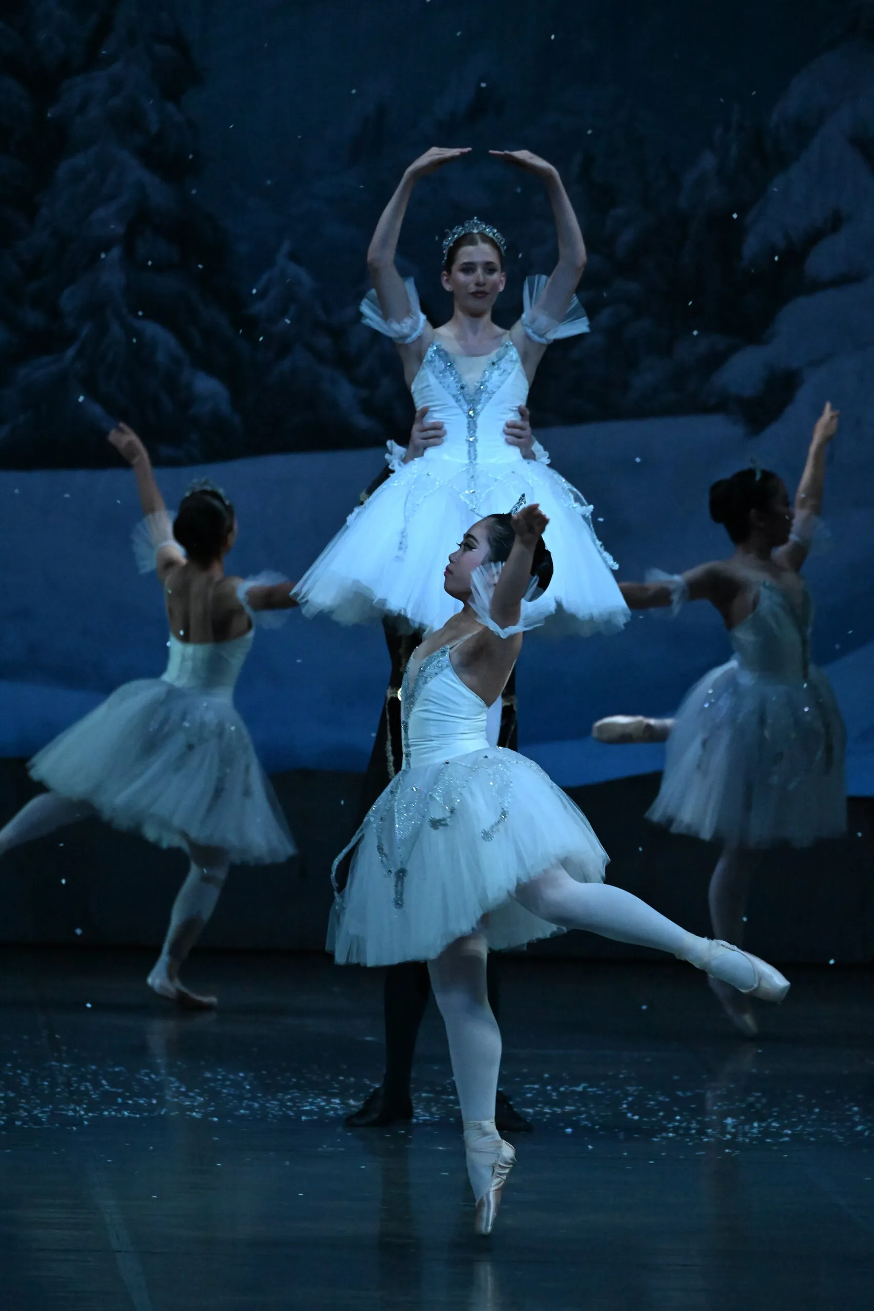 Two dancers in white tutus at the centre of the corps de ballet, under the snow.