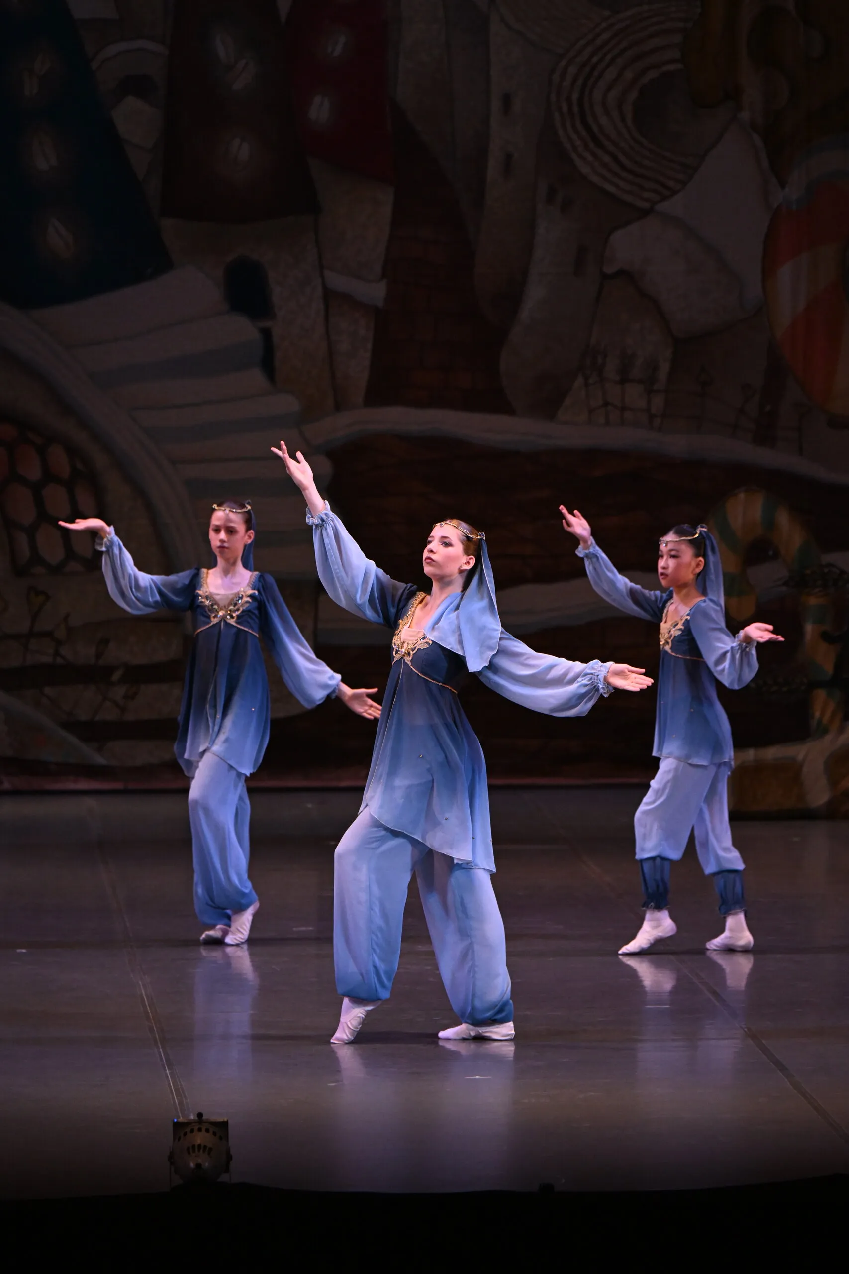 Trois danseuses en costumes bleu gris, bras levés.