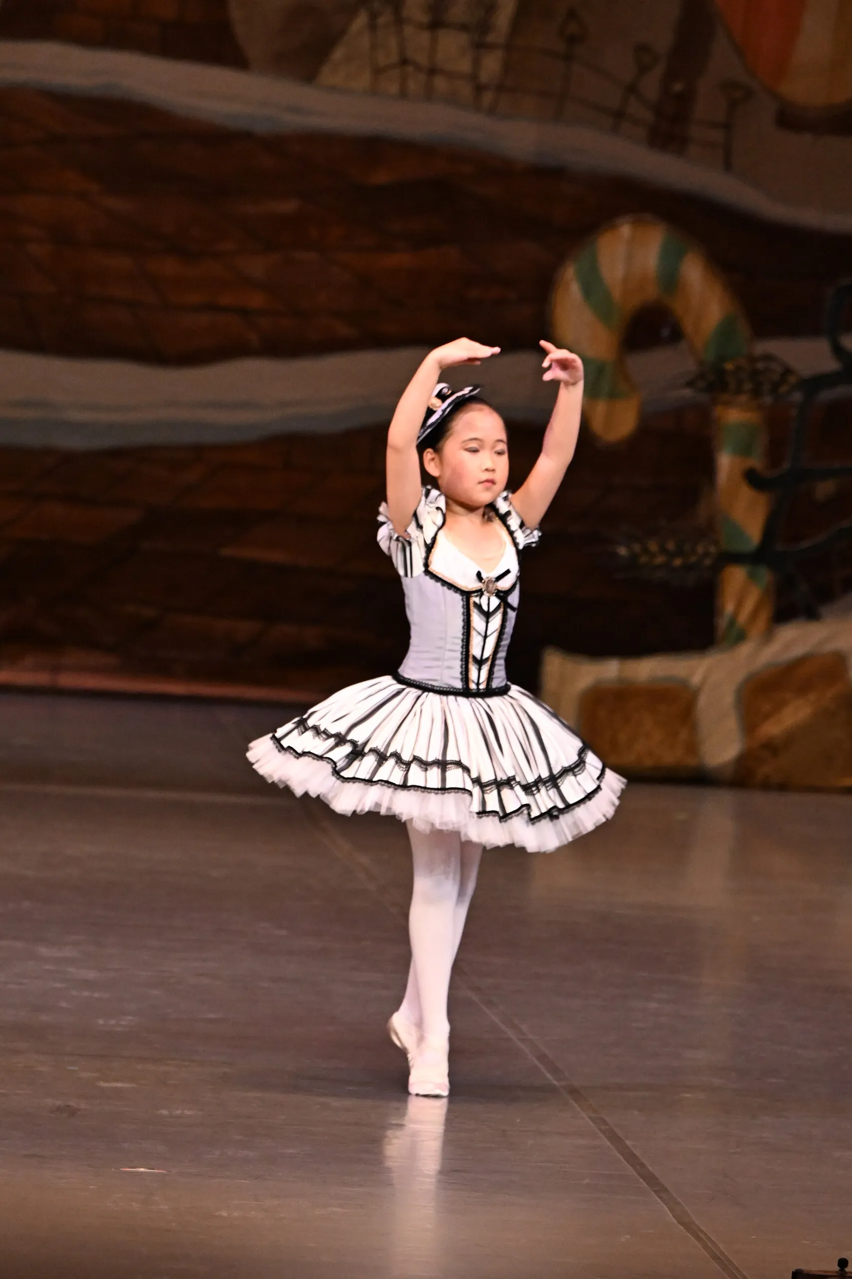 Une élève en tutu noir et blanc, en retiré, figure entière.