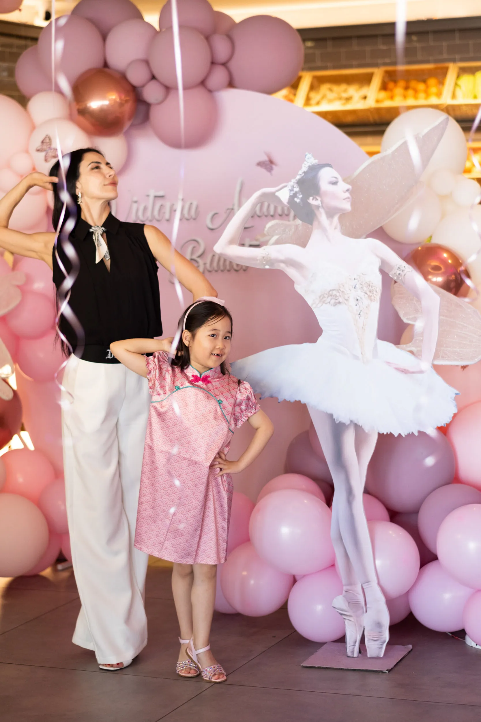 The founder and a young student mirror the pose of the ballerina on the backdrop.