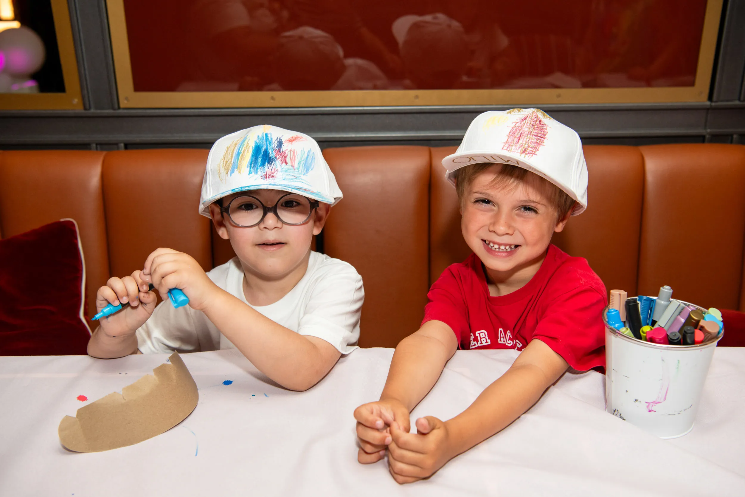 Two boys proudly show the caps they have decorated.