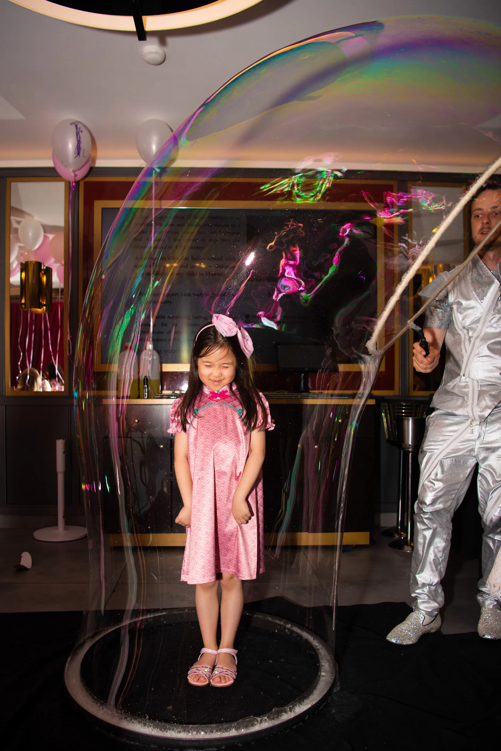 A delighted child standing inside a giant bubble.