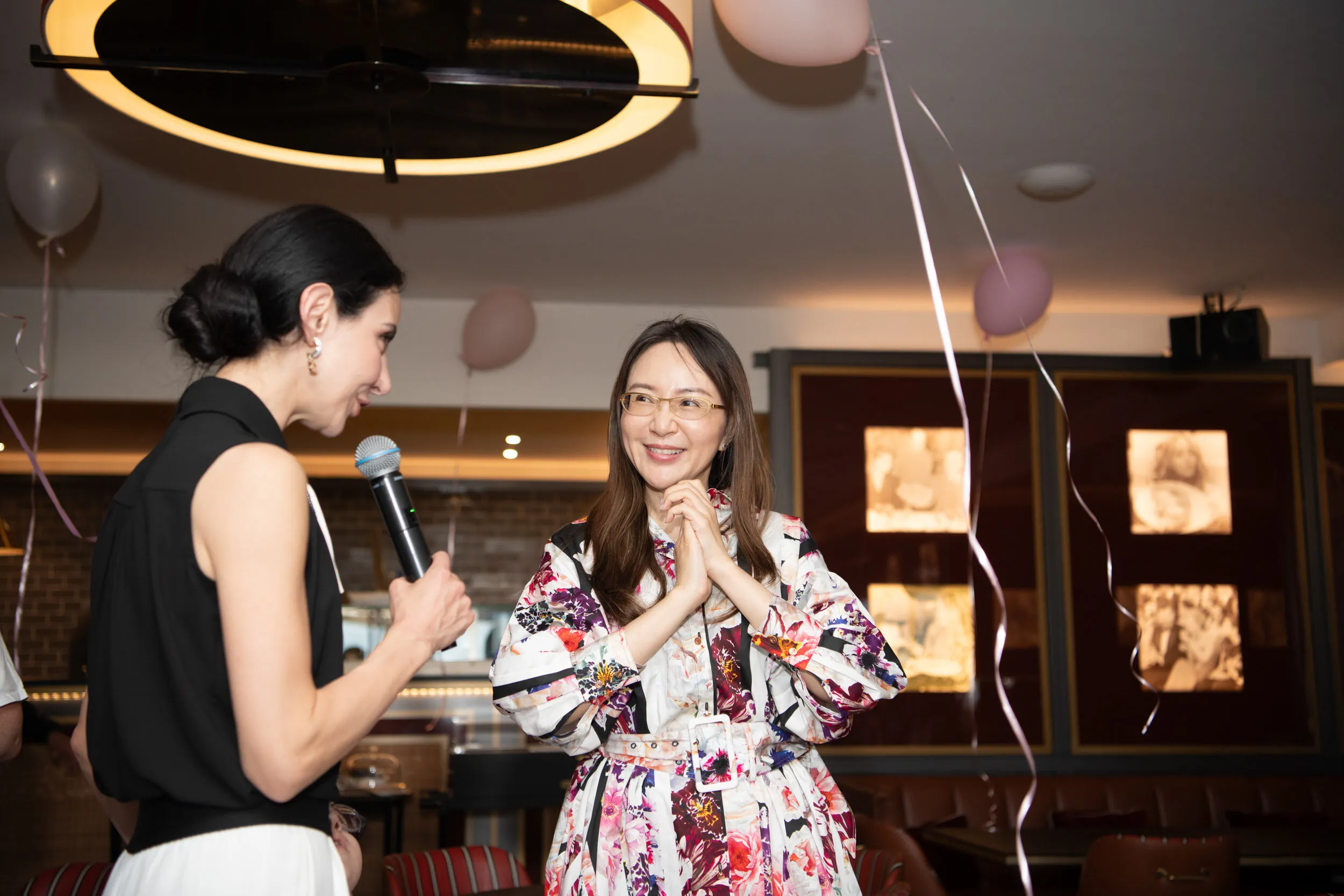 The founder speaks into the microphone beside a guest.