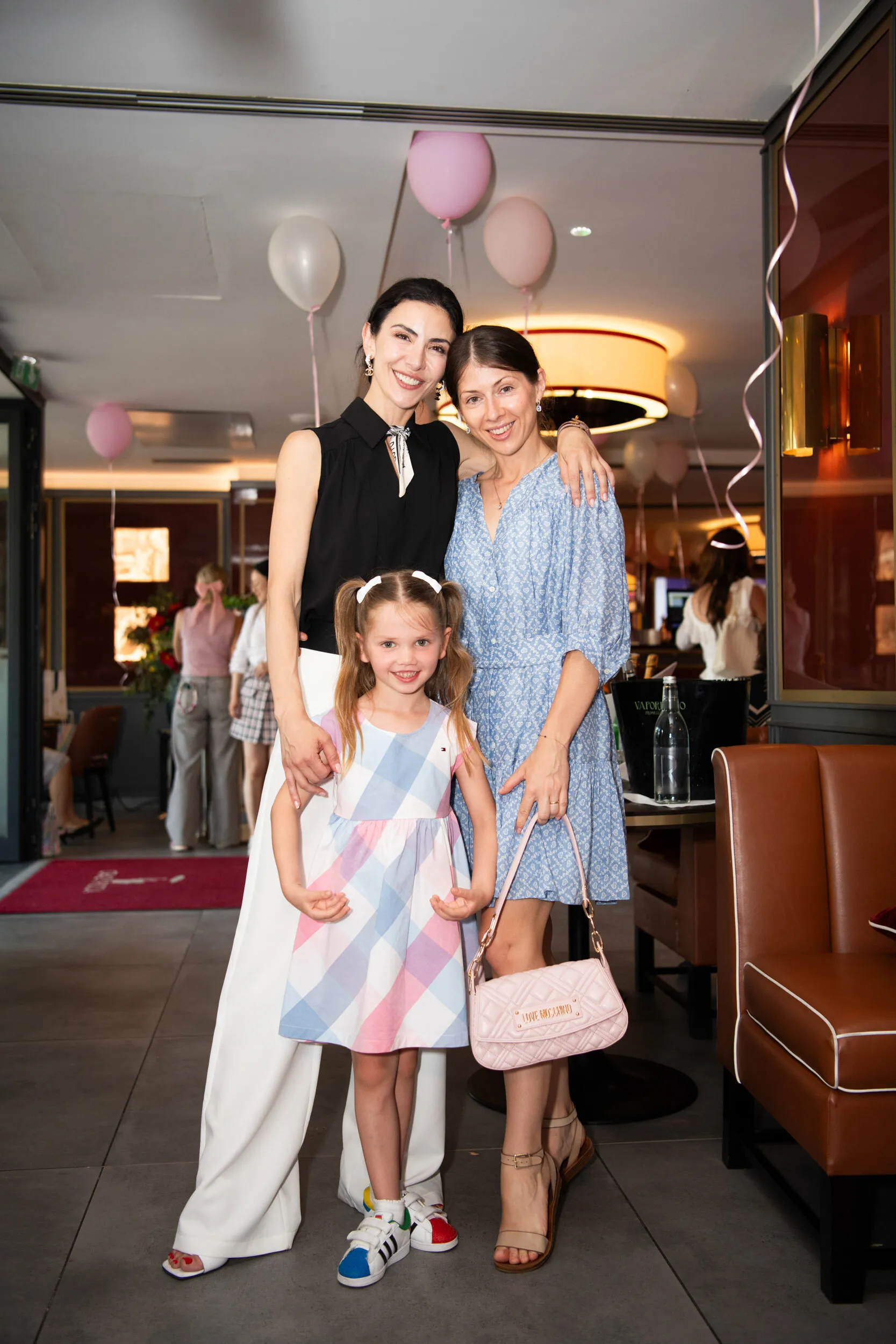 The founder poses with a child and a guest at the entrance to the room.