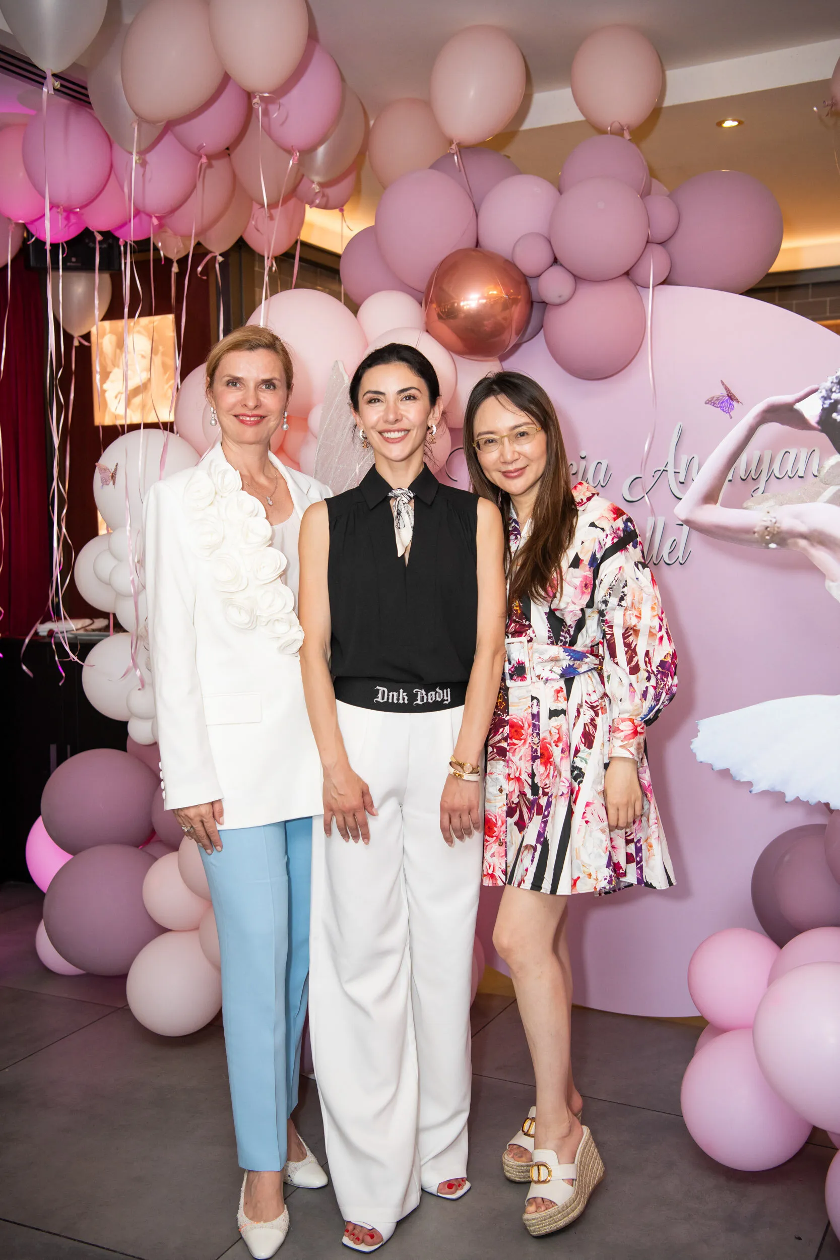The founder with two guests in front of the balloon wall.