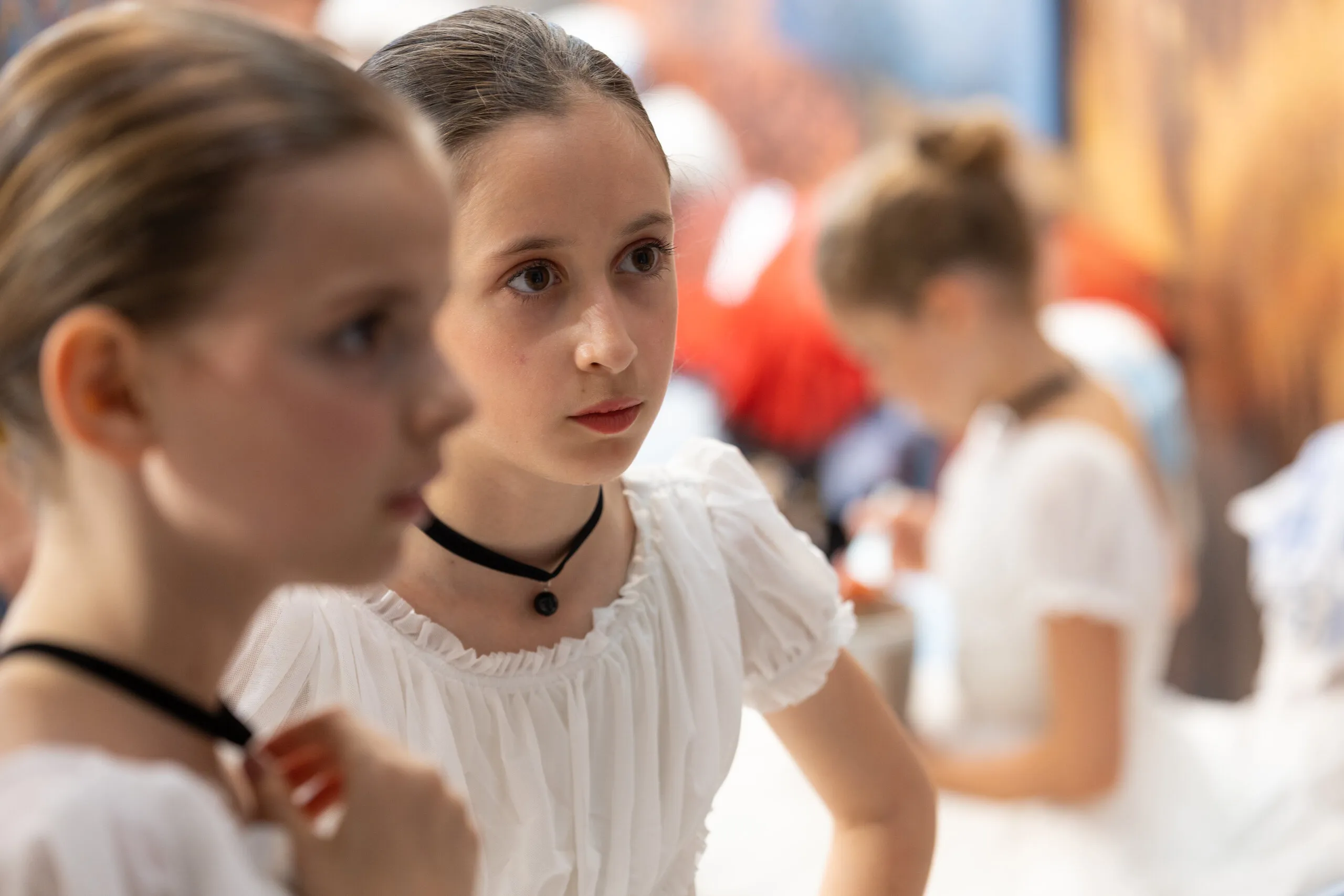 Deux élèves en blouses blanches et ras-de-cou noir, en coulisses avant d'entrer.