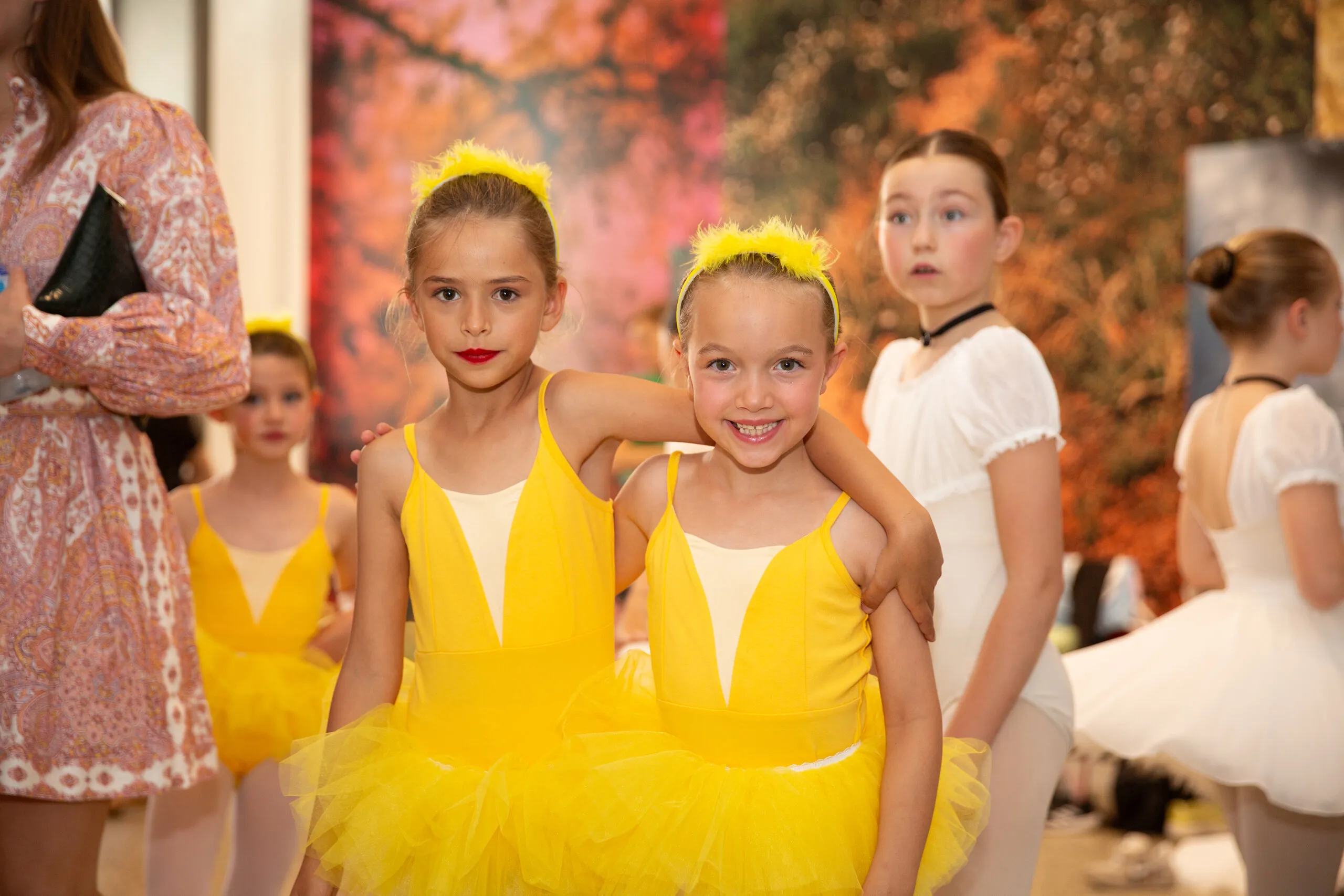 Deux élèves en tutus jaunes, l'une posant la tête sur l'épaule de l'autre.