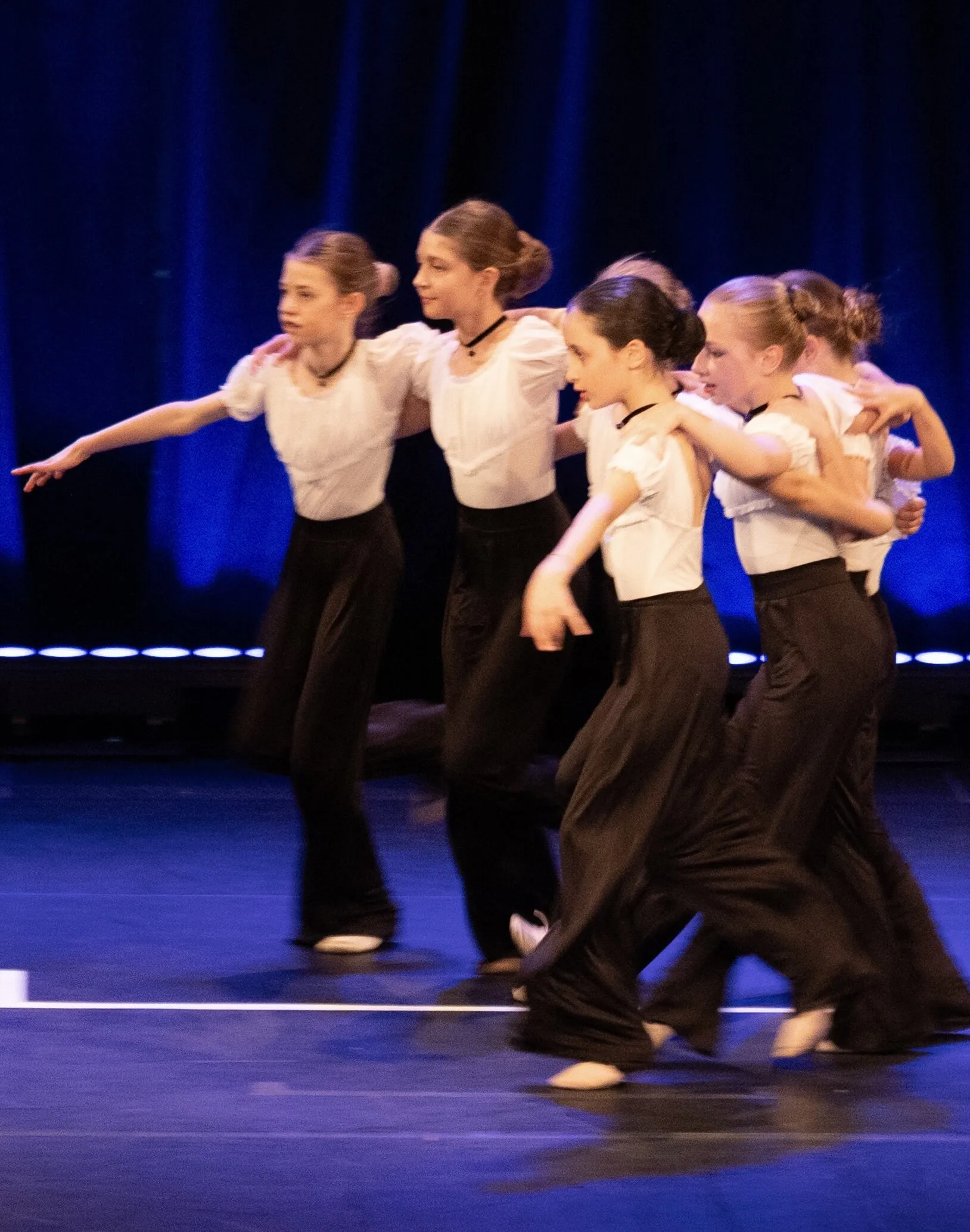Le groupe en pantalons sombres en plein mouvement, dans la lumière bleue.