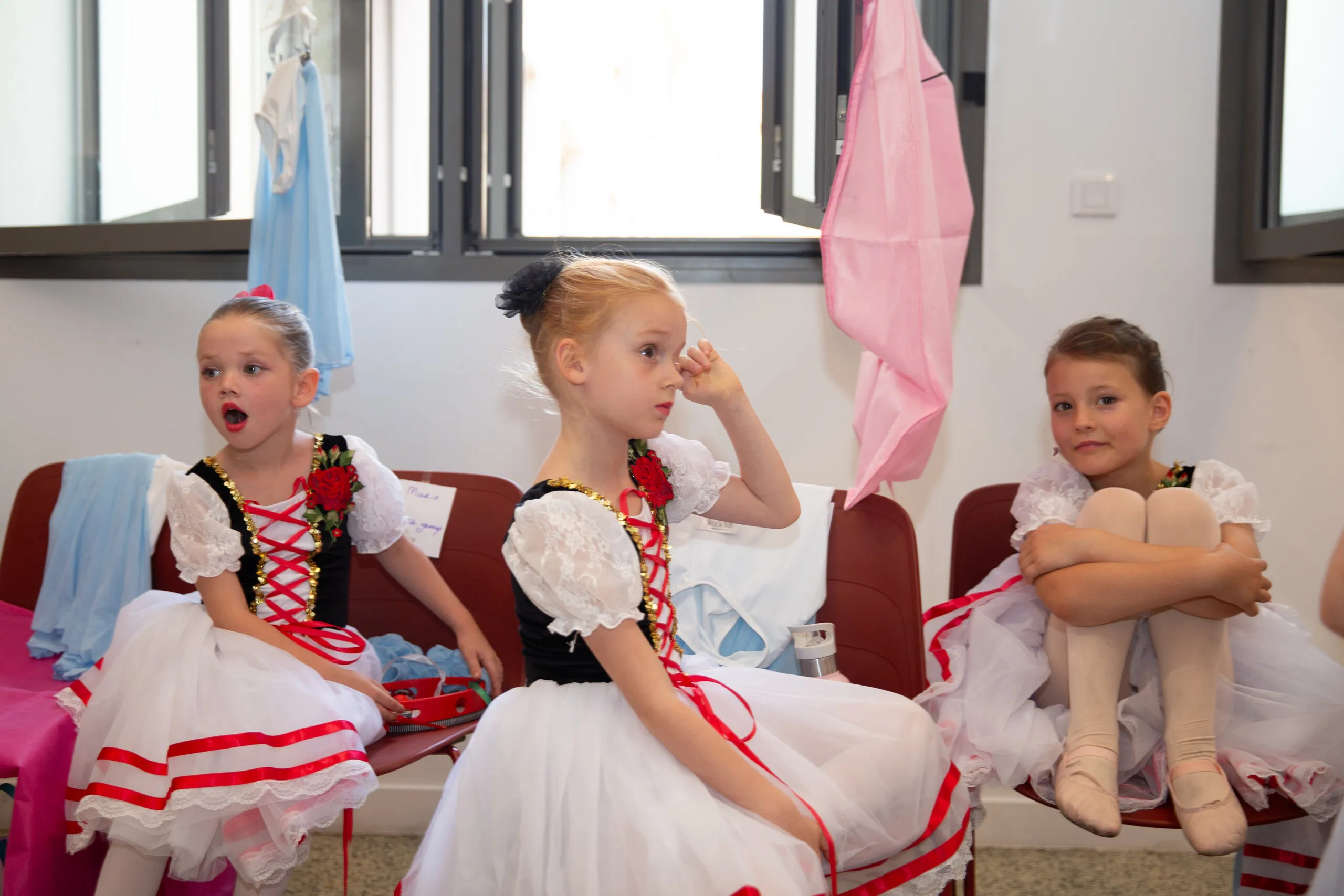 Trois enfants en costume de caractère, assis en coulisses, en attendant.