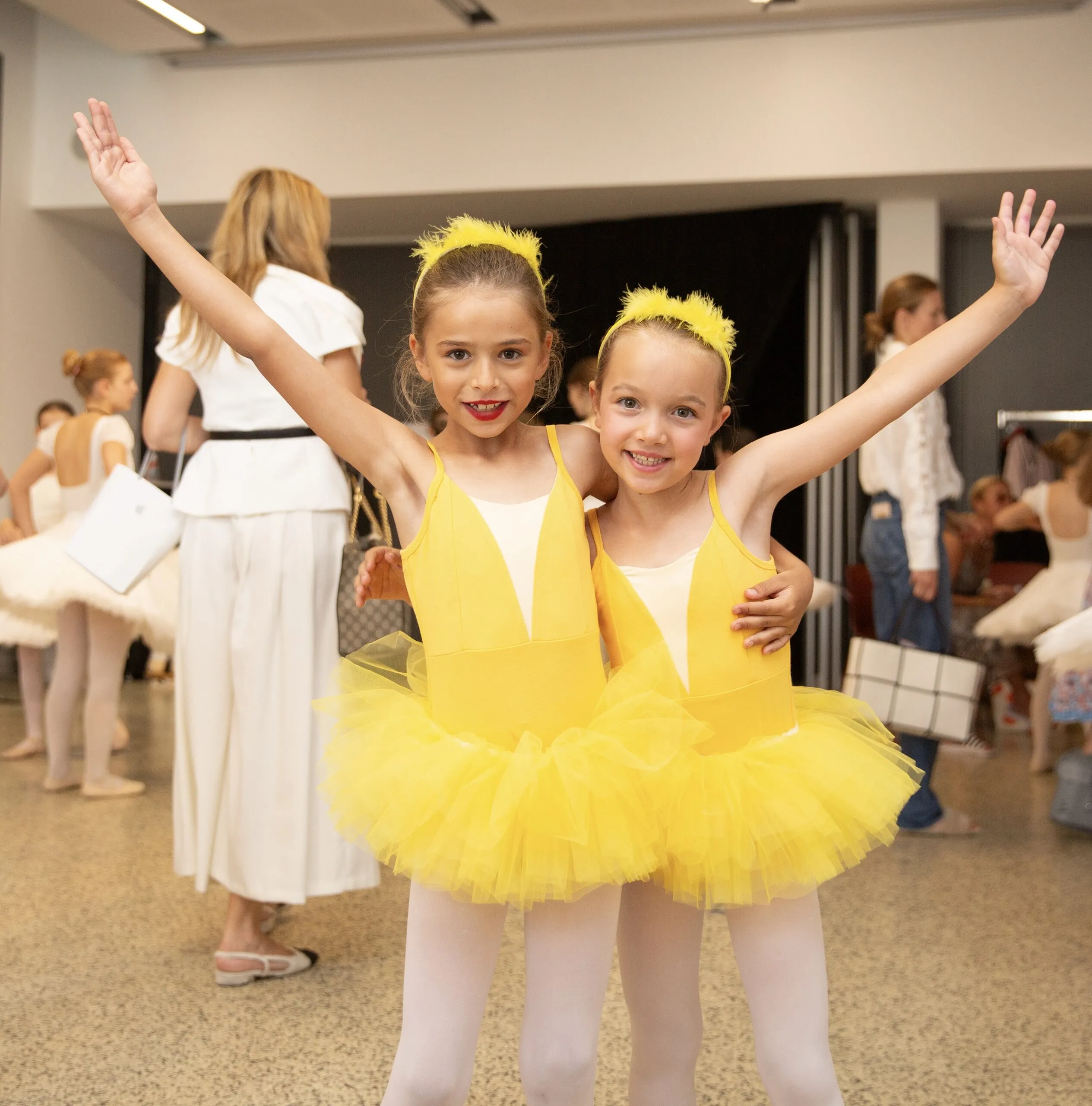 Deux petites en jaune, les bras levés, dans le hall.