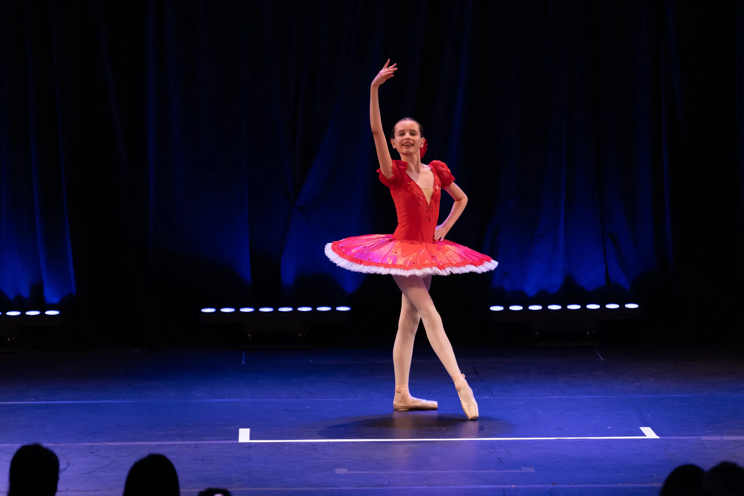 Une soliste en tutu rouge et rose, en arabesque.