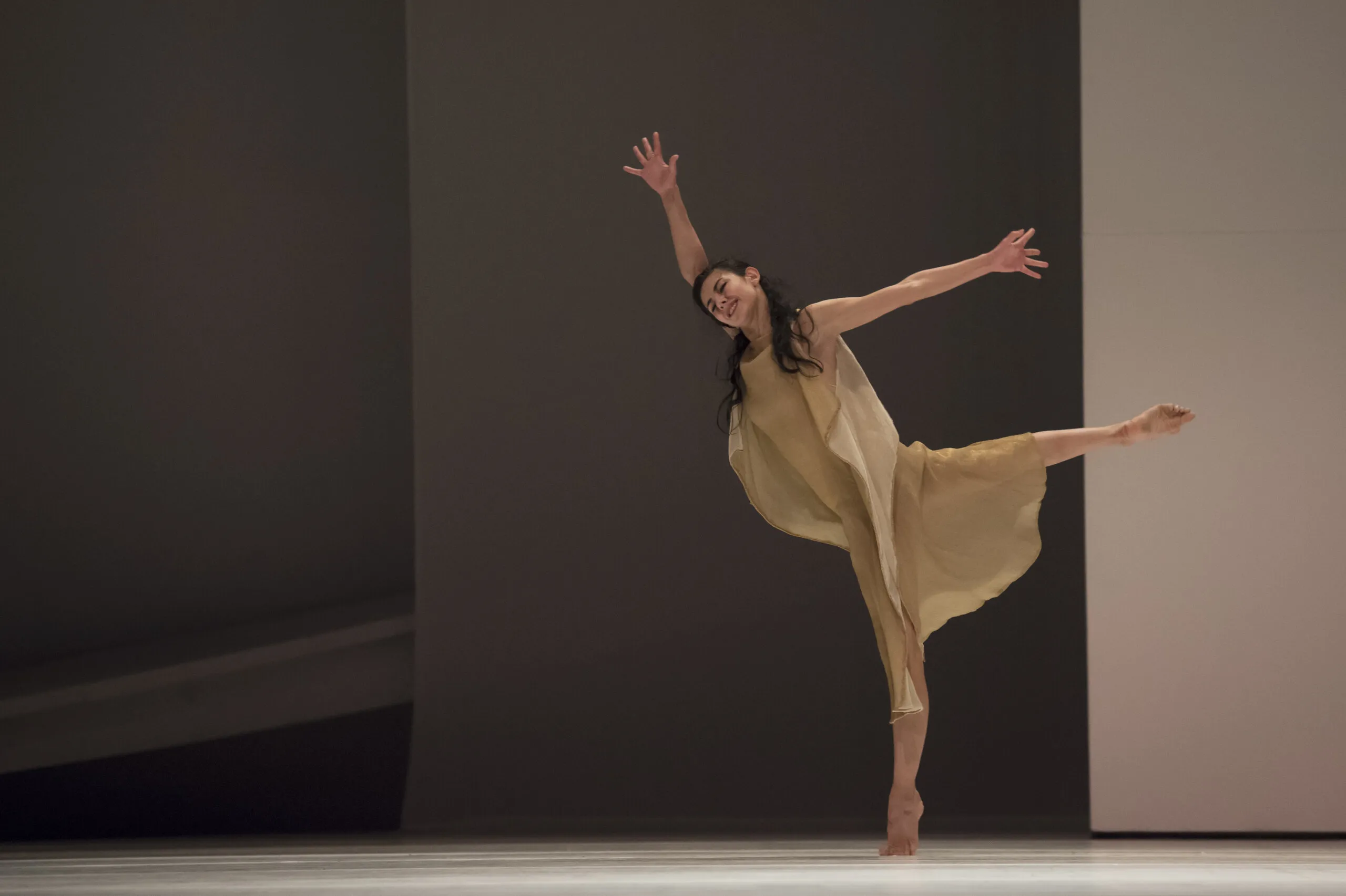 Victoria en arabesque, les cheveux libres, en robe dorée, dans une lumière chaude.