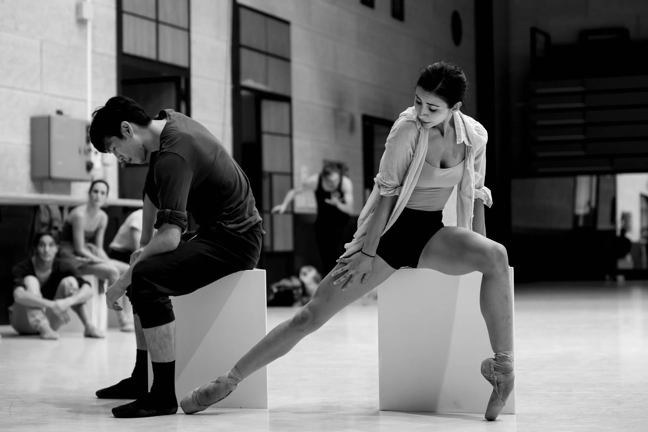 Victoria en studio de répétition, la jambe étirée, aux côtés d'un danseur.