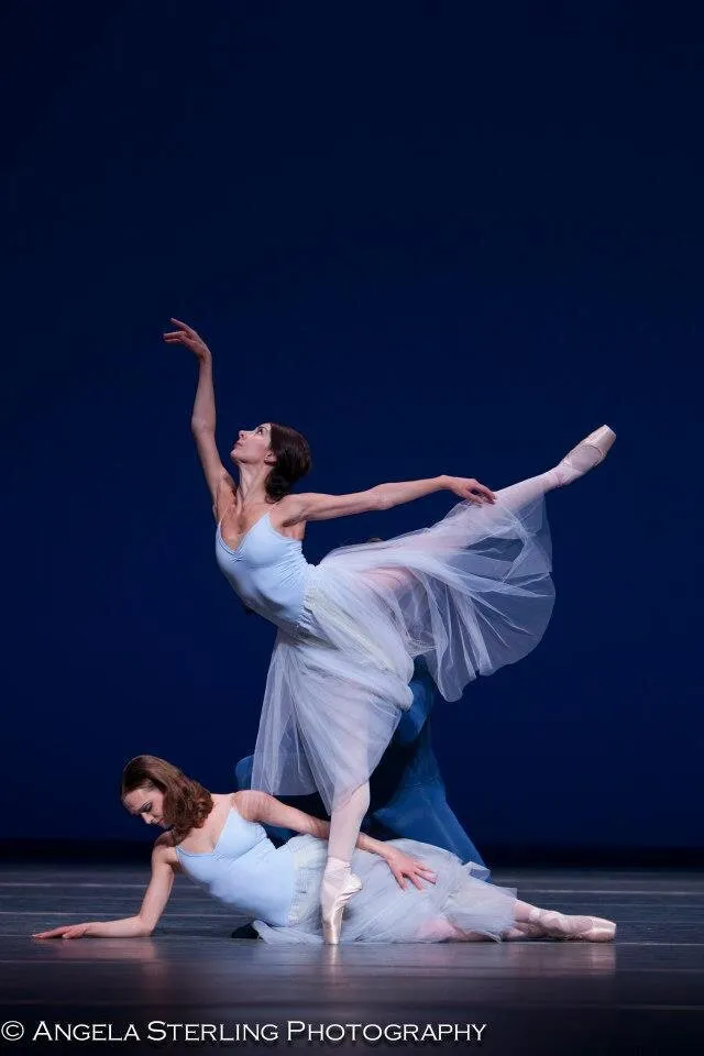 Victoria en tutu romantique blanc, penchée sur pointes, une autre danseuse agenouillée à ses pieds.
