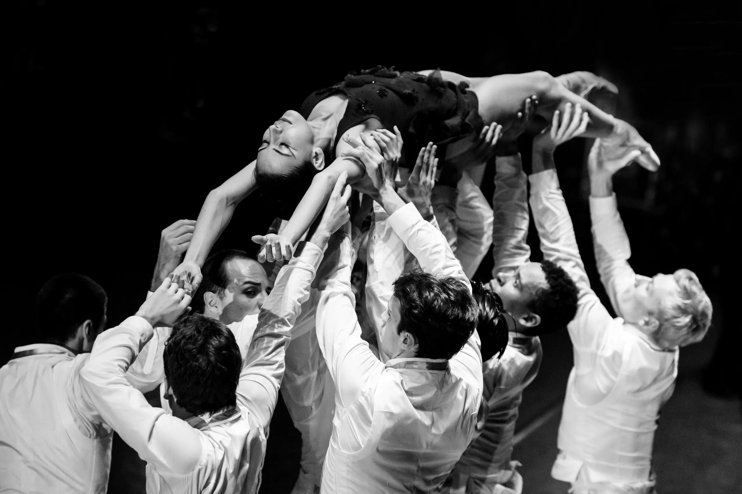 L'ensemble des danseurs porte une danseuse au-dessus des têtes, en noir et blanc.