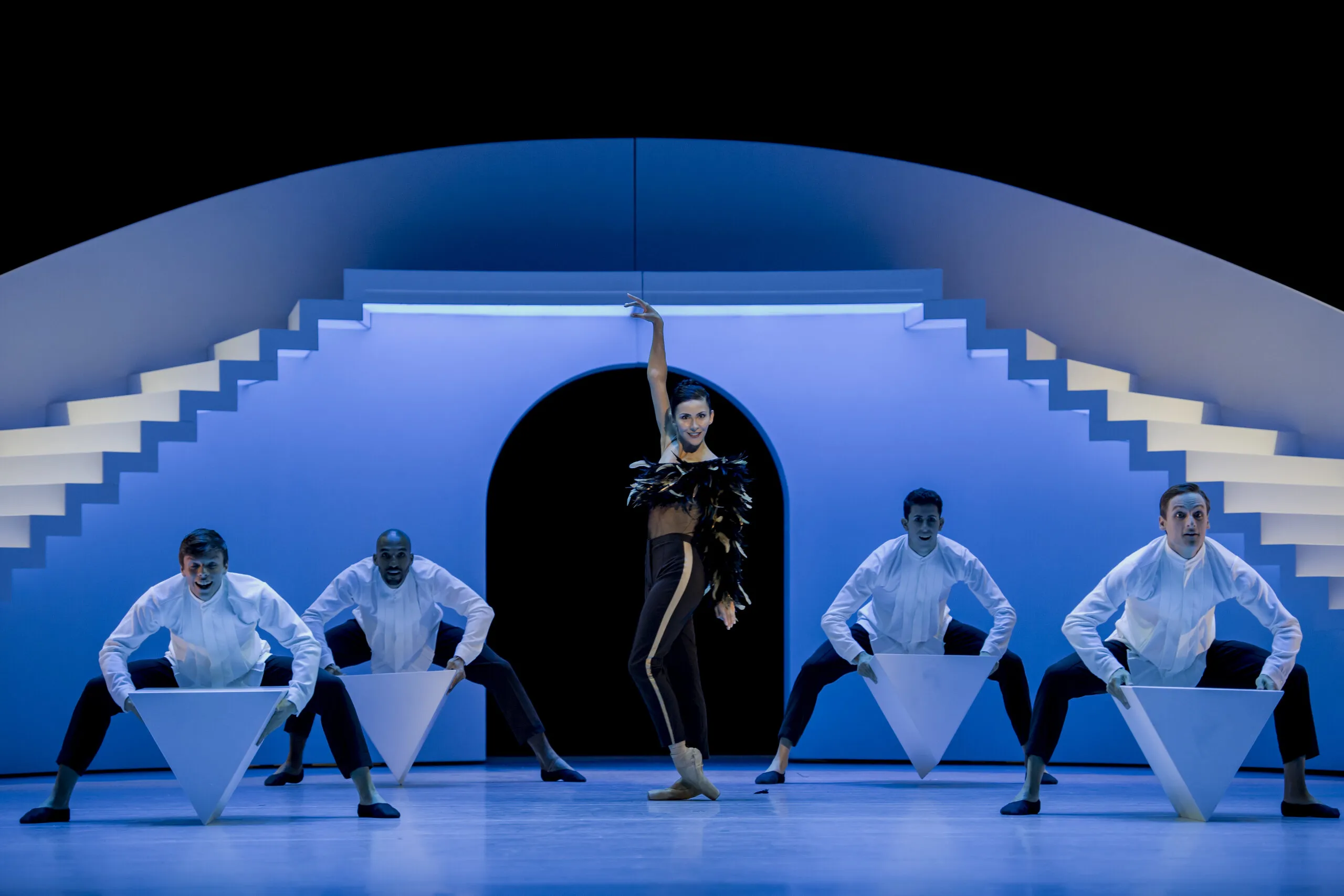 Victoria seule au centre d'un décor bleu à double escalier, quatre danseurs assis de part et d'autre.