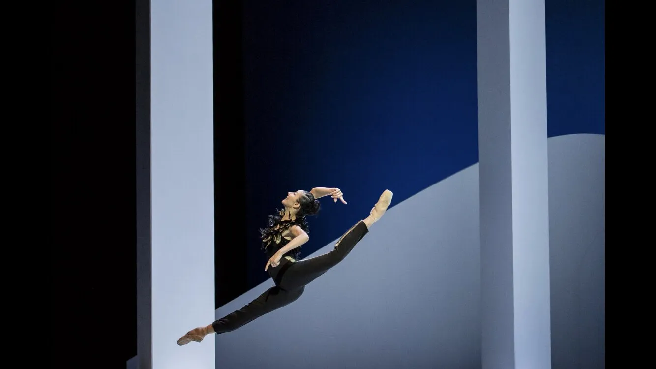 Une danseuse en plein vol horizontal, entre les volumes blancs et bleus du décor.