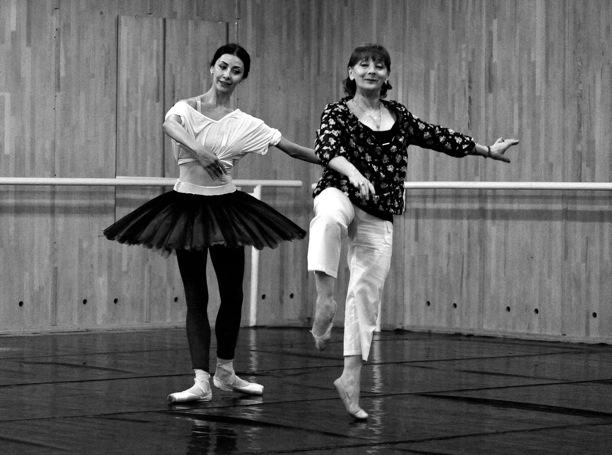 Victoria en tutu noir et sa répétitrice reprennent le même geste, côte à côte, en noir et blanc.