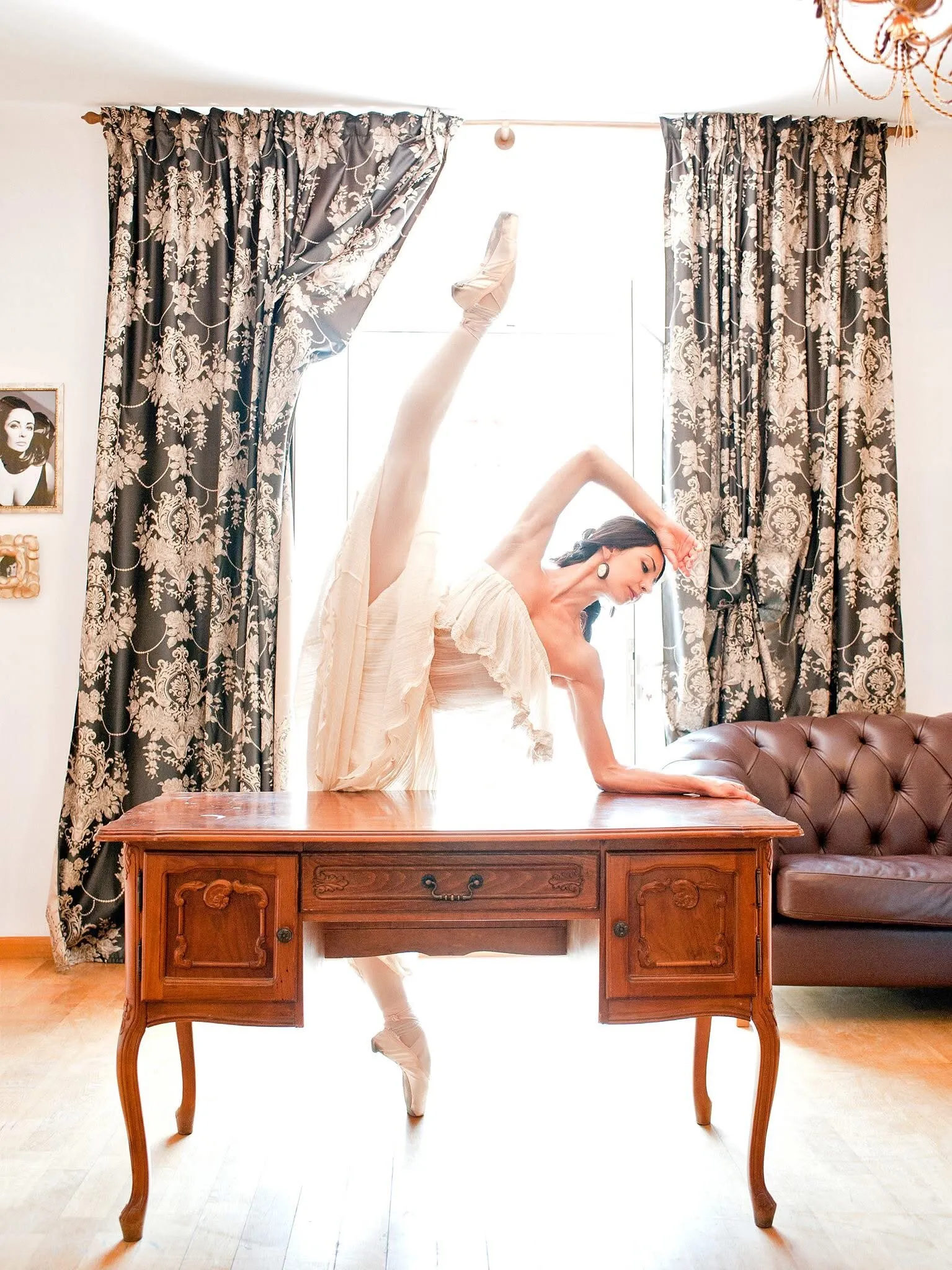 Victoria en penché sur un bureau ancien, dans la lumière d'une haute fenêtre.